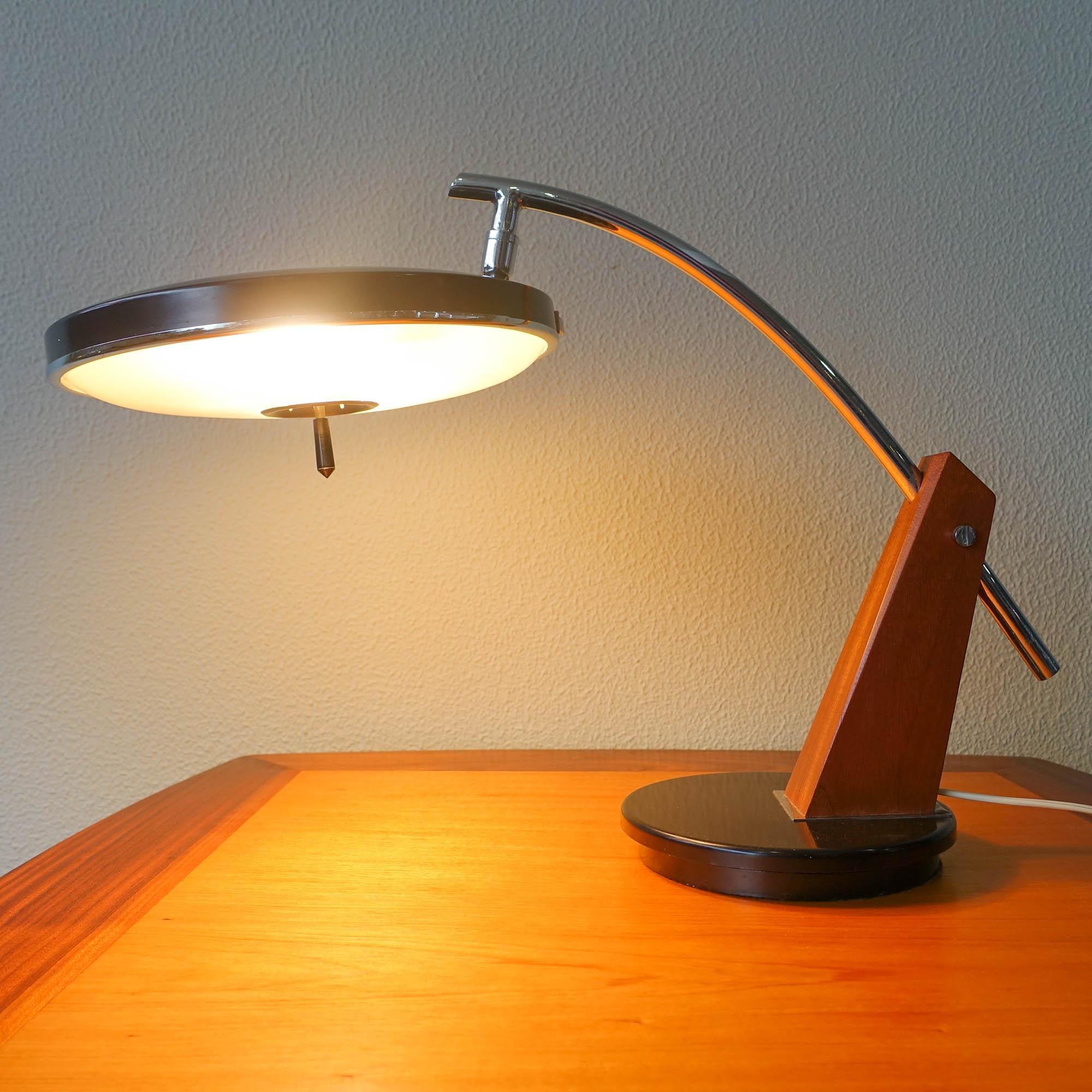 This unusual model of desk lamp was designed and manufactured by Lupela, in Spain during the 1960's. The lamp has a swiveling base and the shade swivels in all directions as well. The arm is a blend of wood and curved chrome rod. It is equipped with
