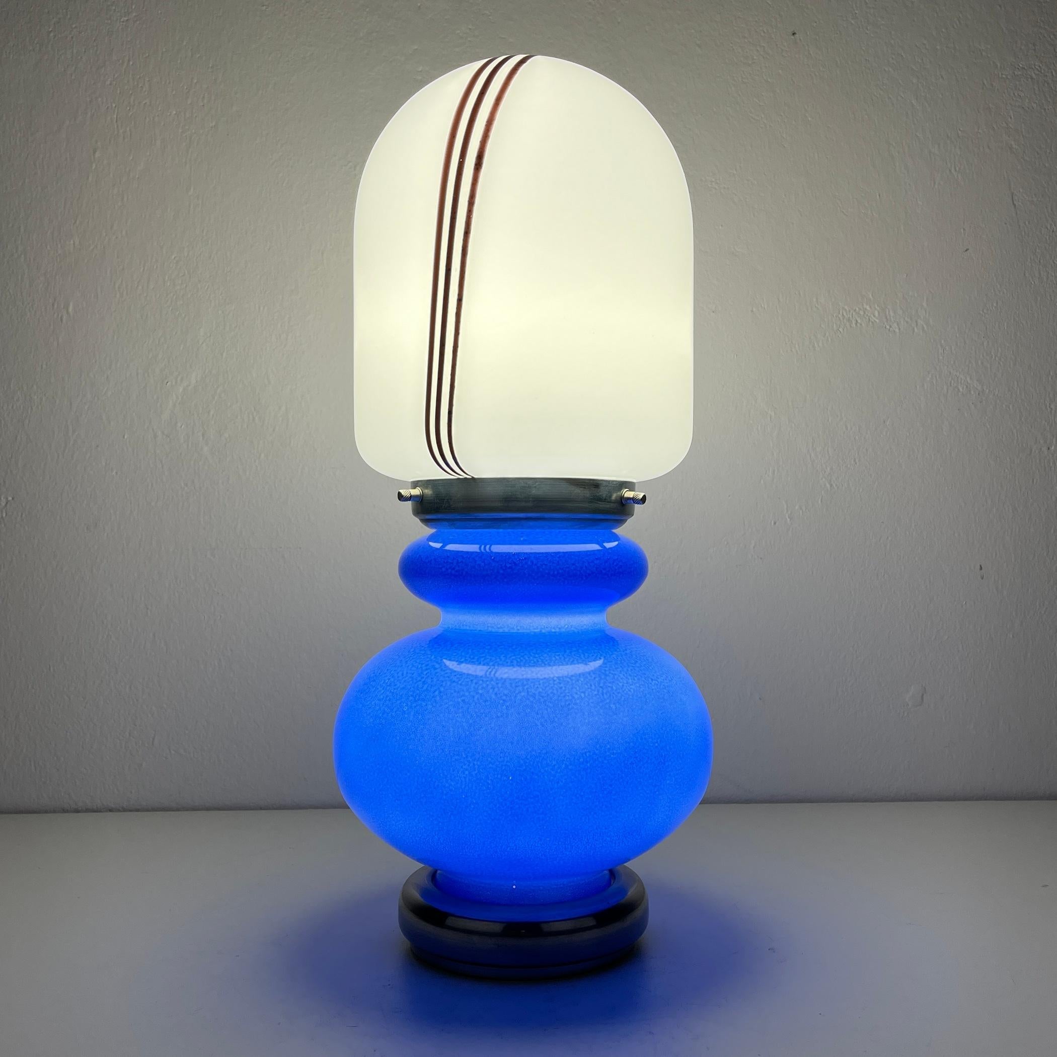 Introducing a charming table lamp, expertly crafted in Italy during the vibrant 1980s. Despite their vintage, this lamp is in impeccable condition, boasting glass that's free from any chips or cracks. This distinctive lamp consist of two glass