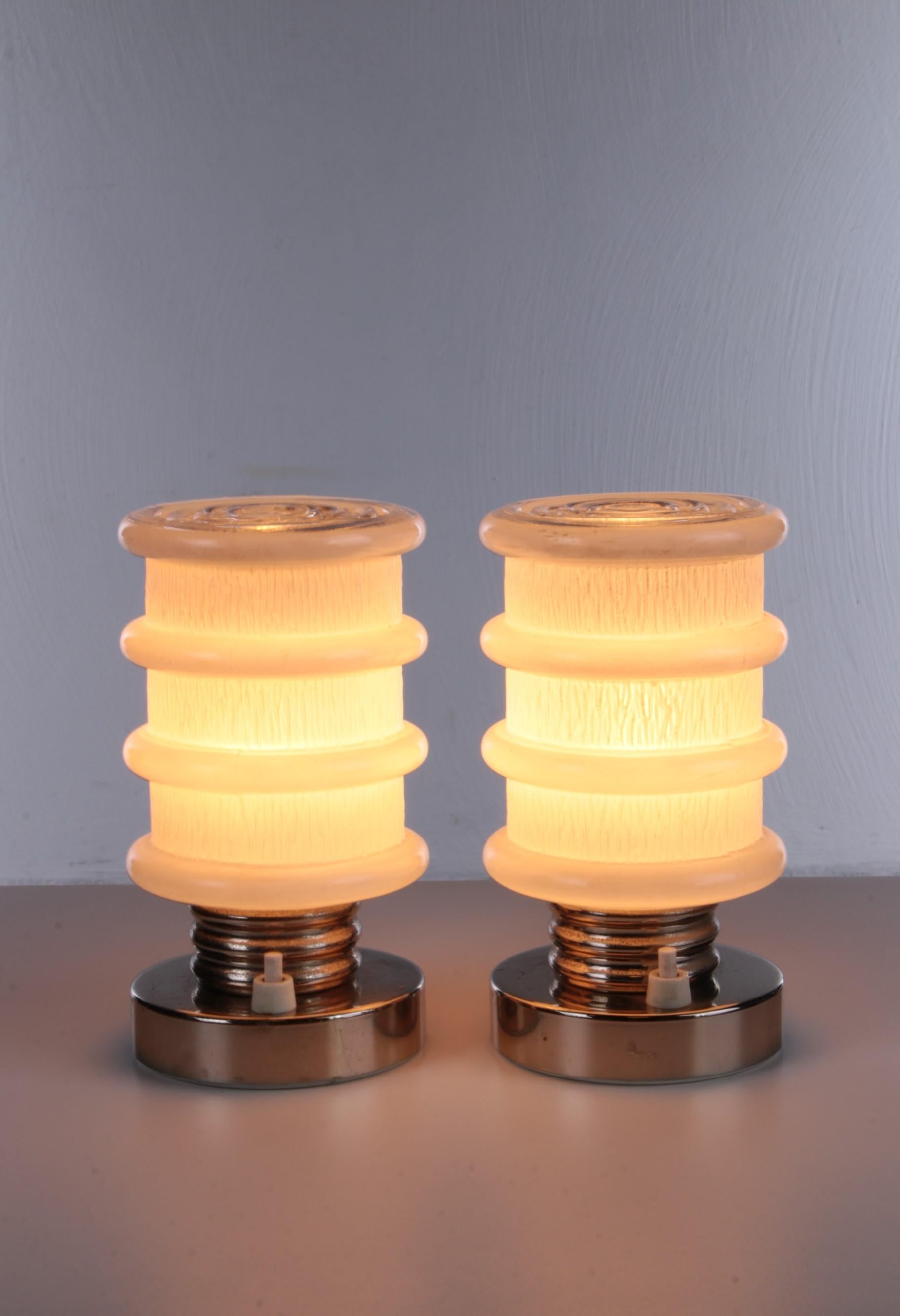 A vintage german table lamp set made with chrome and white glass, from the 1970s

Beautiful set of two table lamps made of a chrome color base with a small E14 fitting.

The glass is beautiful white milk glass with a wavy design. This gives both