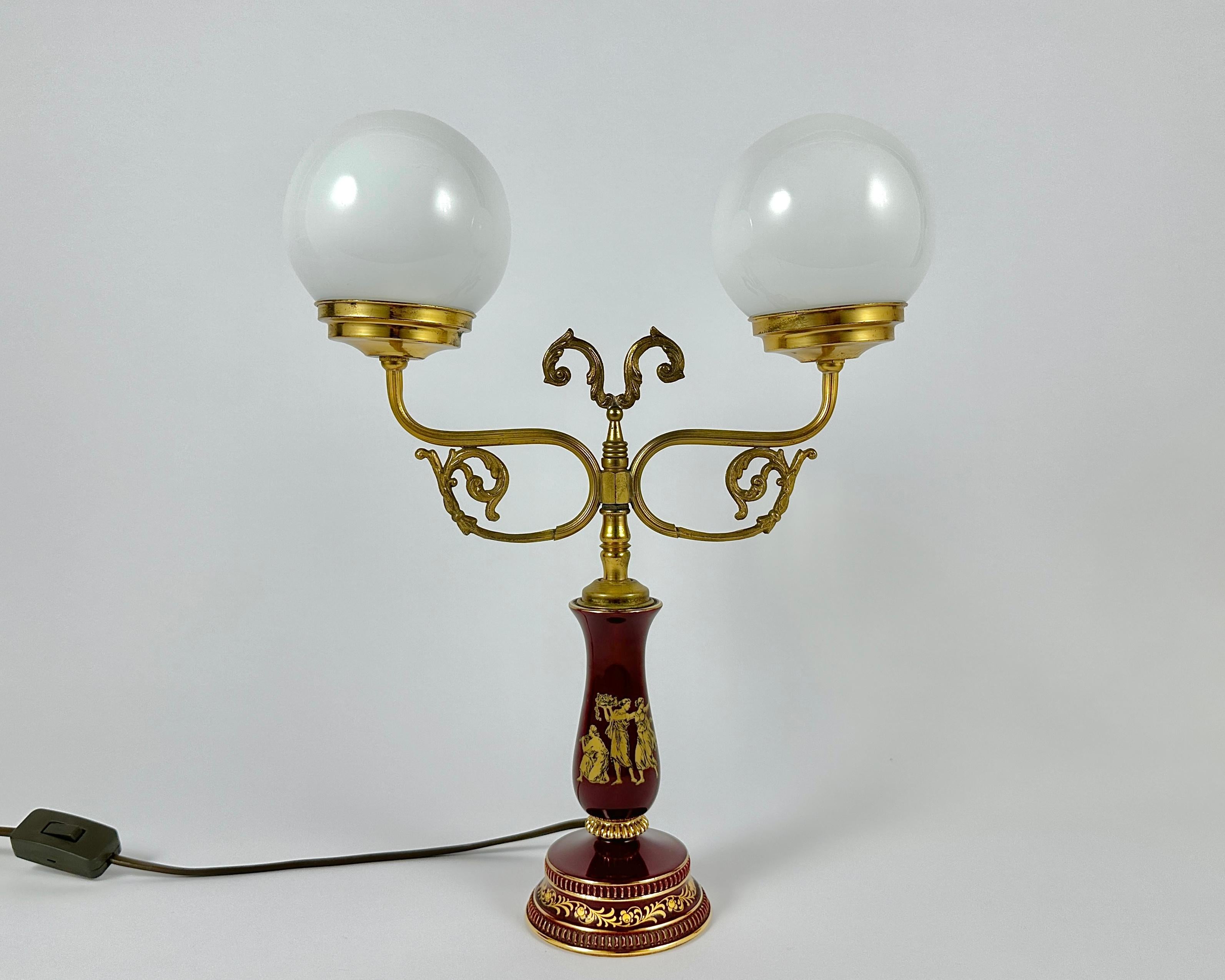 Vintage brass table lamp with two glass shades. This elegant table lamp is a combination of elegance and minimalism.

A fluted column holds two sweepingly curved arms, artful folding spheres from a clamp around the opal matt shades.

This lamp is
