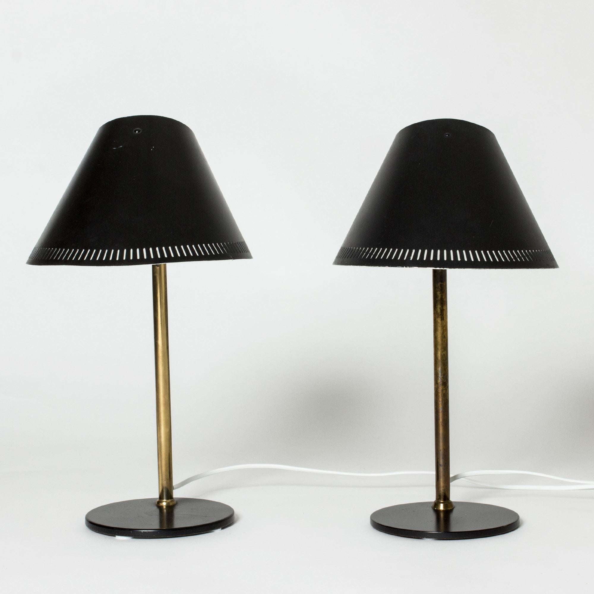 Pair of brass table lamps, model 9227, by Paavo Tynell. Elegant, distinct forms with black lacquered bases and shades. Edges perforated in a graphic pattern.