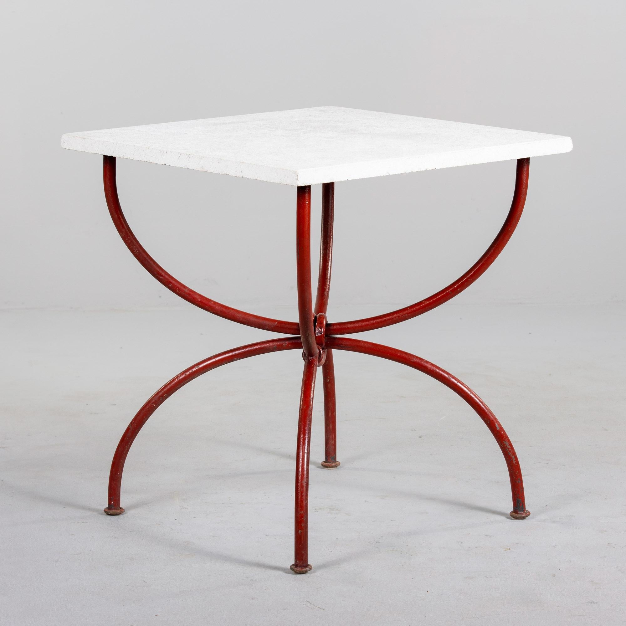 Encontrada en Italia, esta mesa rústica con tablero de piedra caliza blanca y base de metal rojo / tubo de hierro data de la década de 1970. La robusta base/marco tiene bonitas curvas y las patas y brazos acabados en rojo se anudan en el centro.