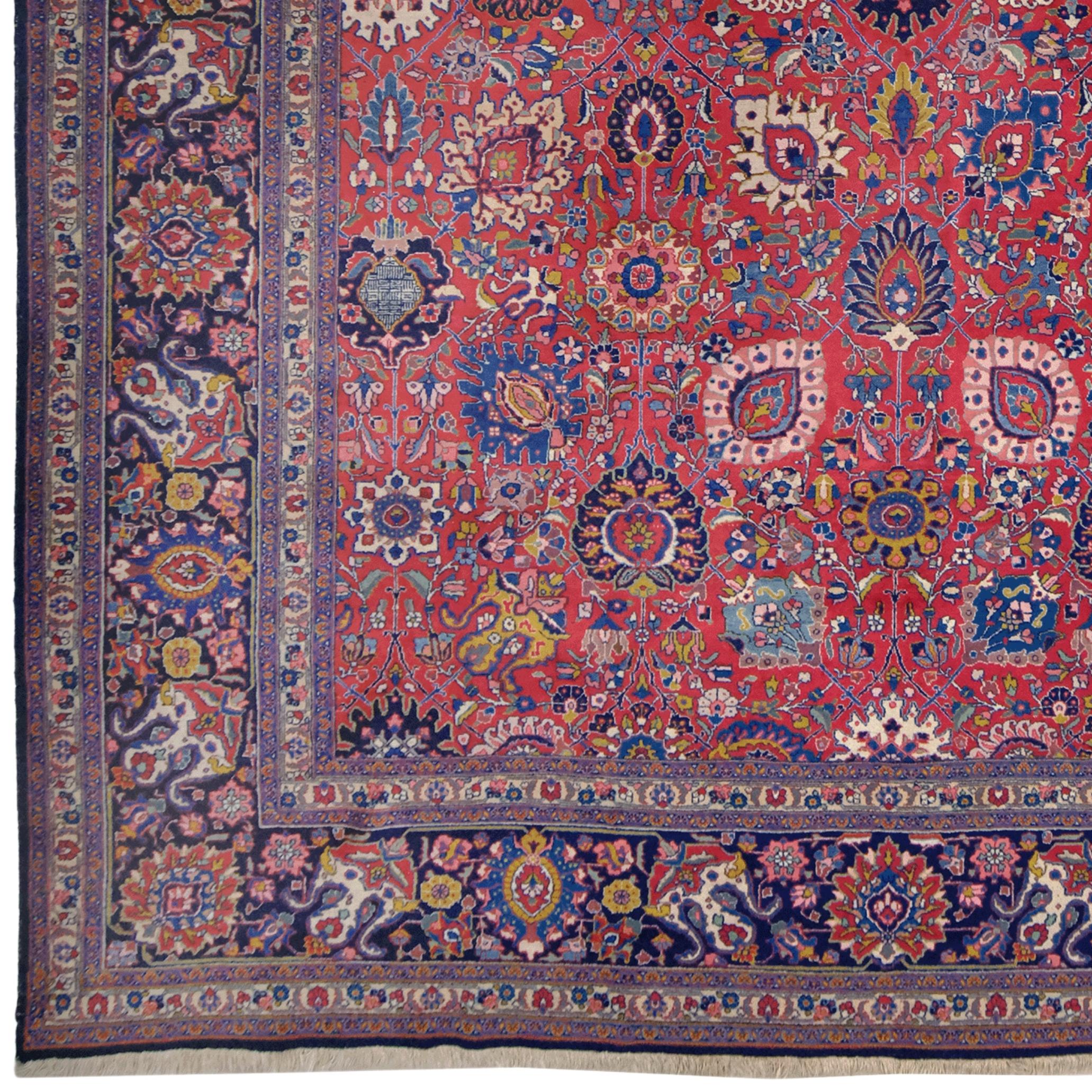 This magnificent vintage Tabriz rug was hand-woven in the Middle East in the early 20th century. Its striking red, blue, and gold tones reflect the characteristic patterns of the Tabriz region.

Measuring approximately 352 cm x 453 cm, this rug
