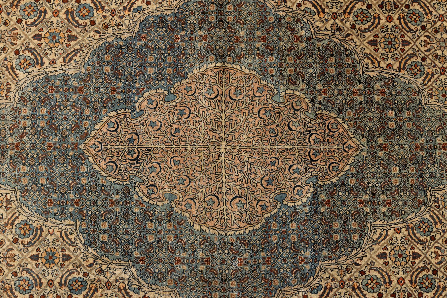 This vintage handwoven wool carpet brings an intricate medallion composition and a remarkably balanced palette of soft blues, warm beige, and subtle earth tones. Its design centres on an elegant scalloped medallion filled with finely articulated