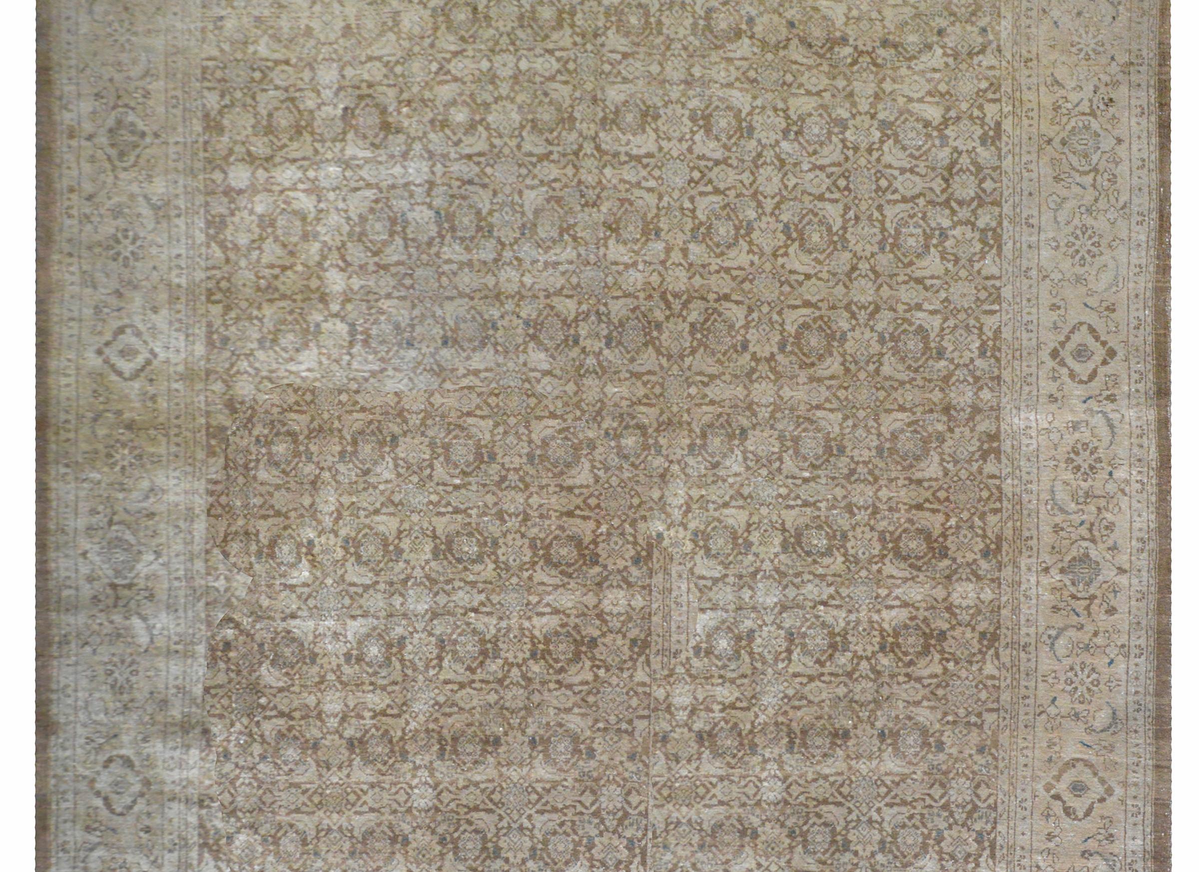 A beautiful vintage Persian Tabriz rug with an all-over trellis floral and leaf pattern surrounded by a wide large-scale floral patterned border. This rug has been given an antiqued wash to fade the colors.