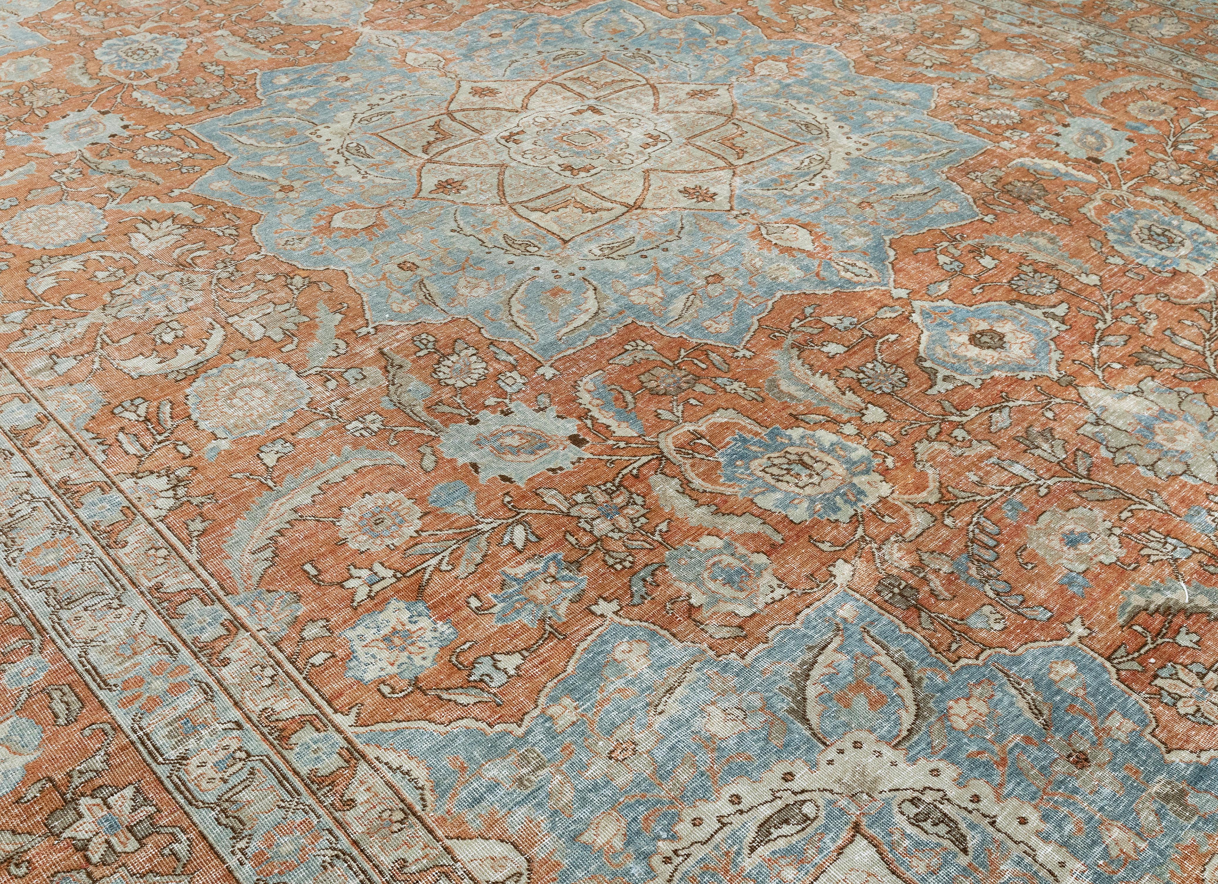 Exemple exquis de l'artisanat persan du milieu du XXe siècle, ce tapis Tabriz vintage du nord-ouest de l'Iran présente un grand médaillon central entouré de motifs floraux et botaniques complexes. Tissé par des artisans qualifiés à partir de laine