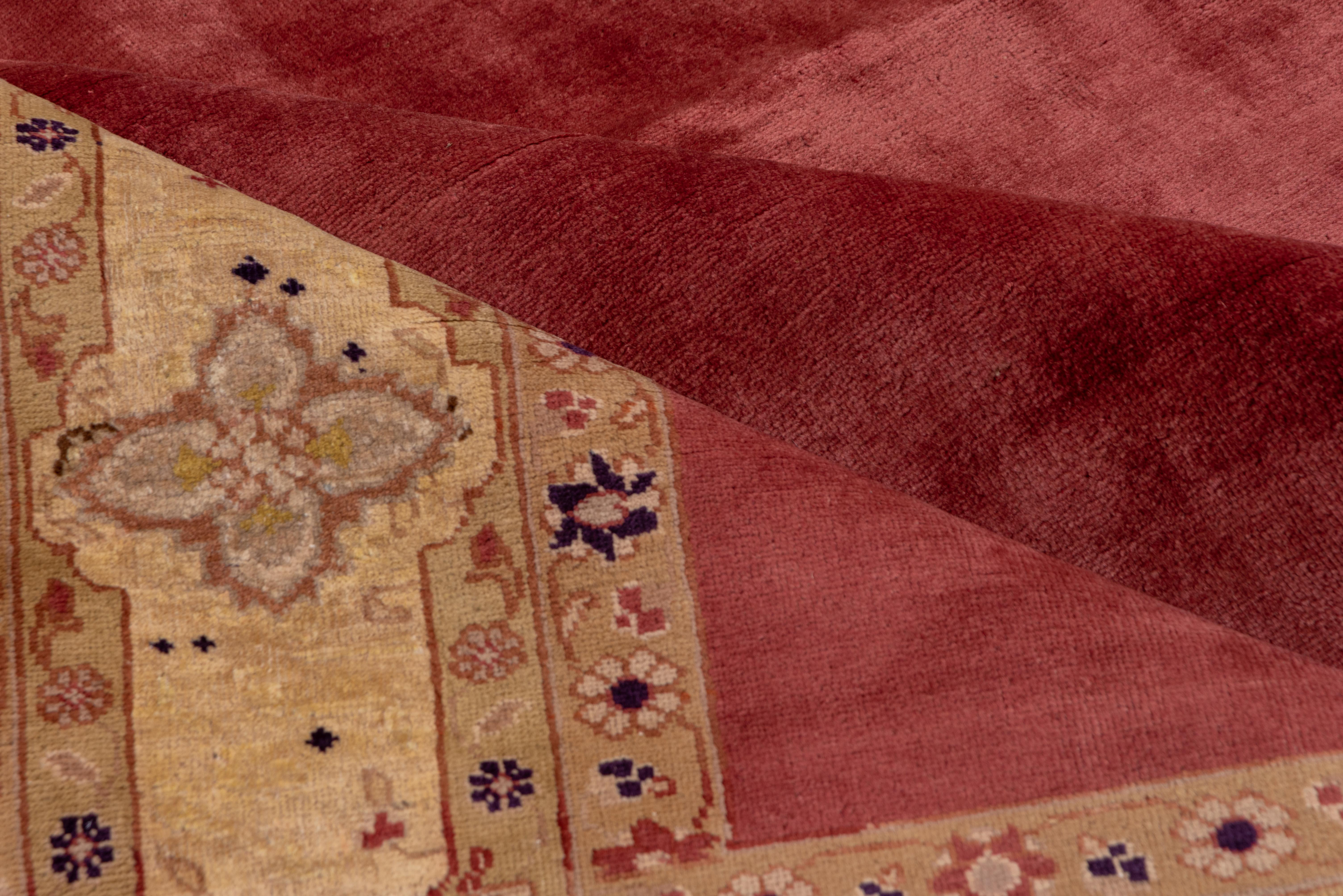 This vintage Tabriz rug showcases an elegant minimalist approach with its expansive rose-colored field, inviting a sense of serenity and subtle opulence. The refined composition is framed by a buttery ivory border adorned with stylized palmettes,