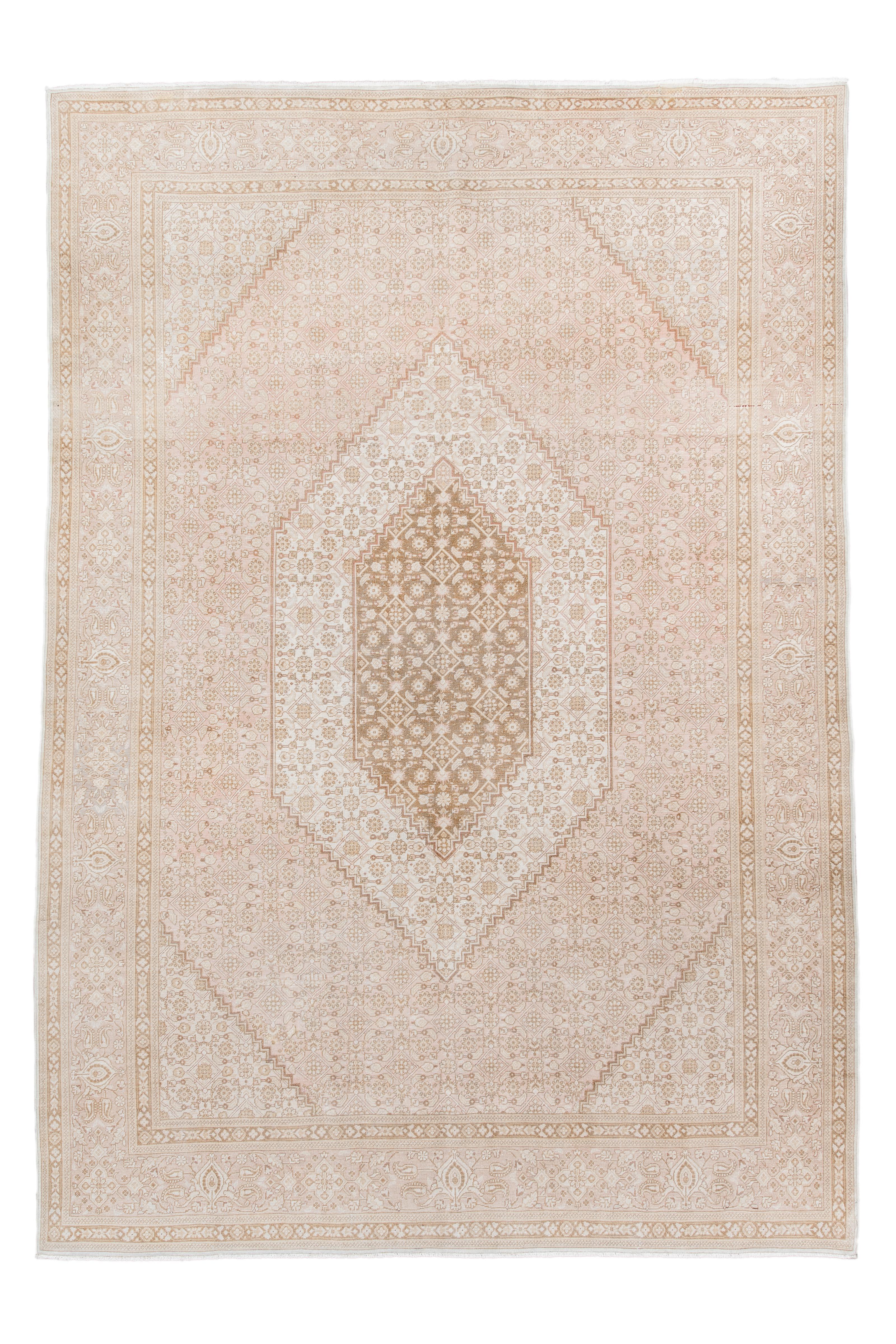 Esta alfombra Tabriz vintage rezuma refinada elegancia con su campo suavemente sonrosado y su medallón floral delicadamente estratificado en marfil y arena. Intrincados rosetones, palmetas y vides enrejadas forman un armonioso motivo en toda la