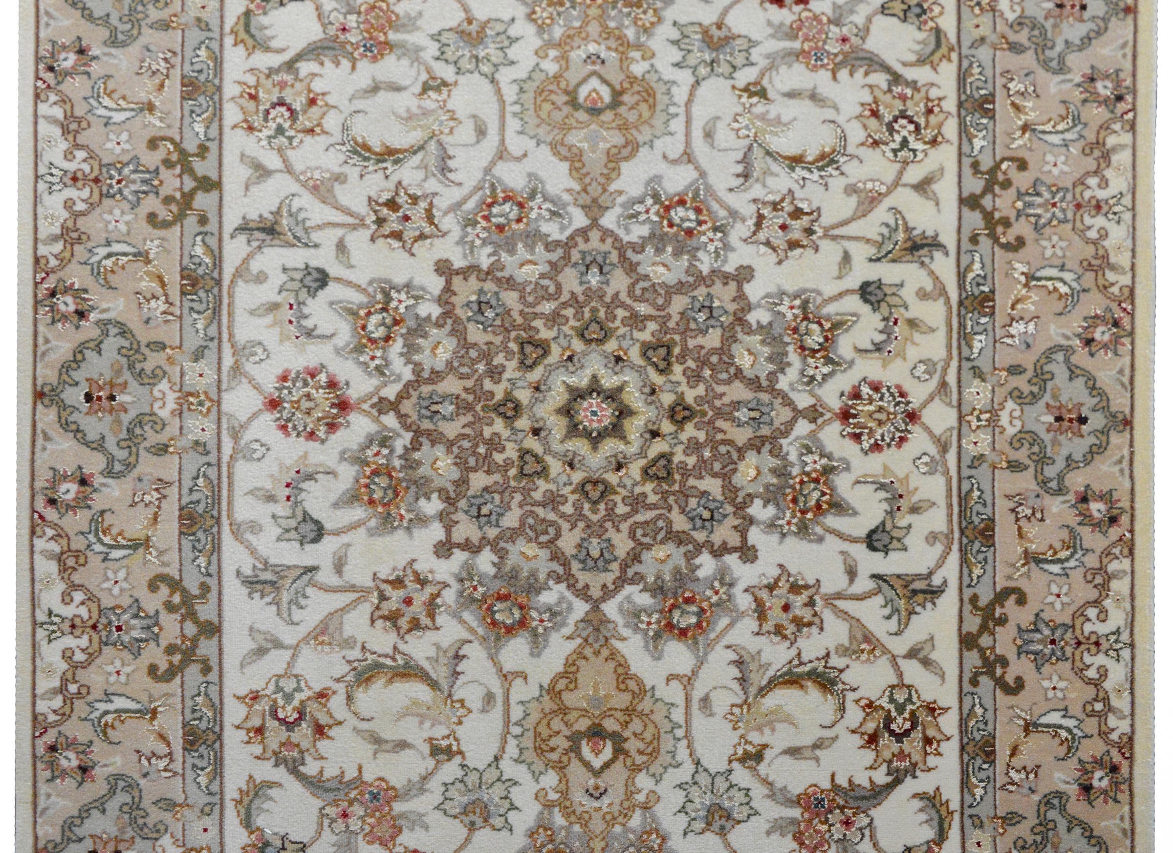 A striking vintage Paksitani hand-knotted Tabriz-style runner woven with a trellis floral pattern in muted reds, greens, golds, and browns, and set against a cream colored background. The border is similar patterned and woven in similar colors s the