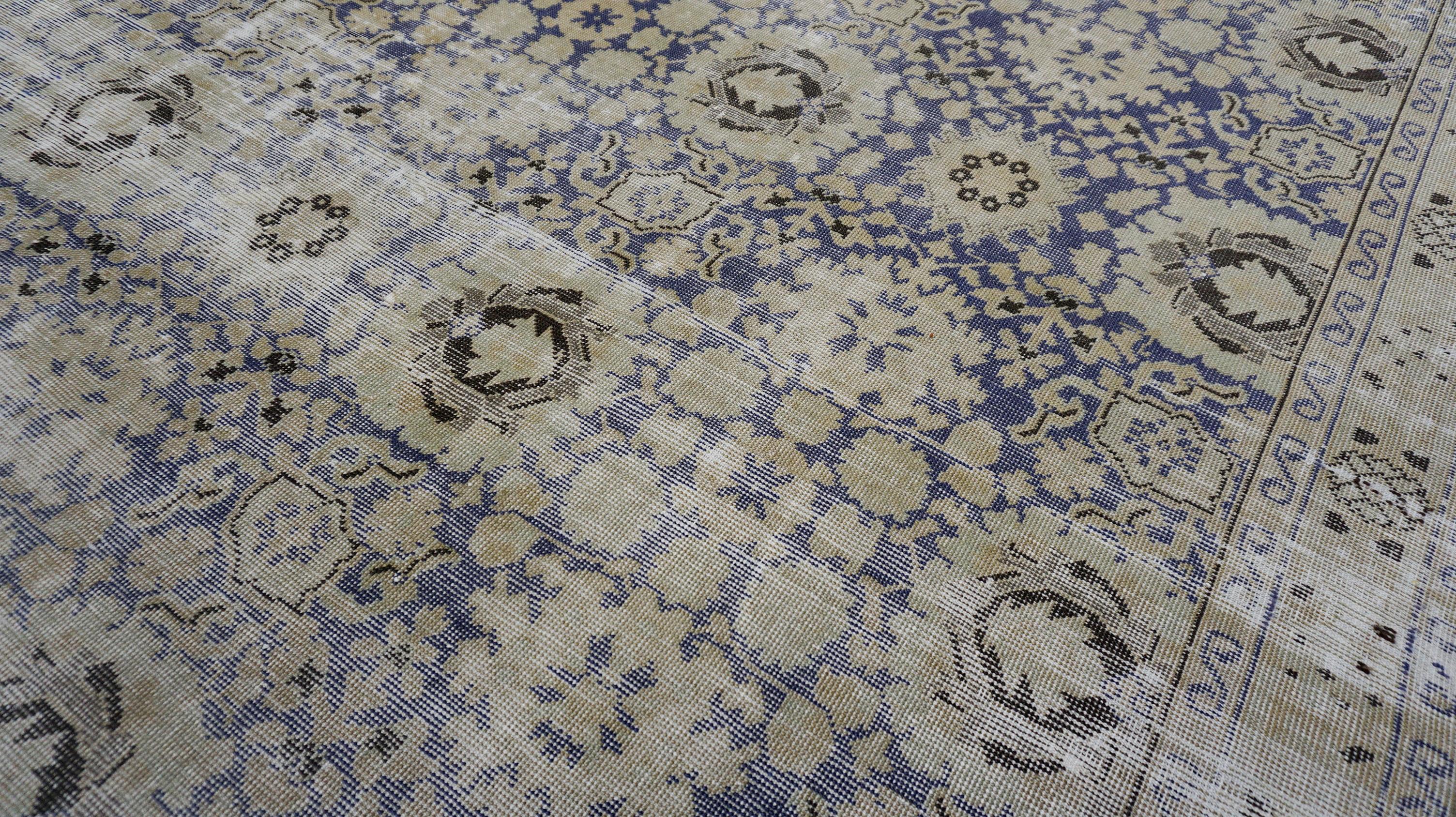 Dieser handgeknüpfte Wollteppich mit seiner gealterten Ästhetik fängt die Essenz von gealterter Eleganz und zeitloser Handwerkskunst ein. Das komplizierte Design zeigt eine harmonische Mischung aus geometrischen und floralen Motiven, die durch eine