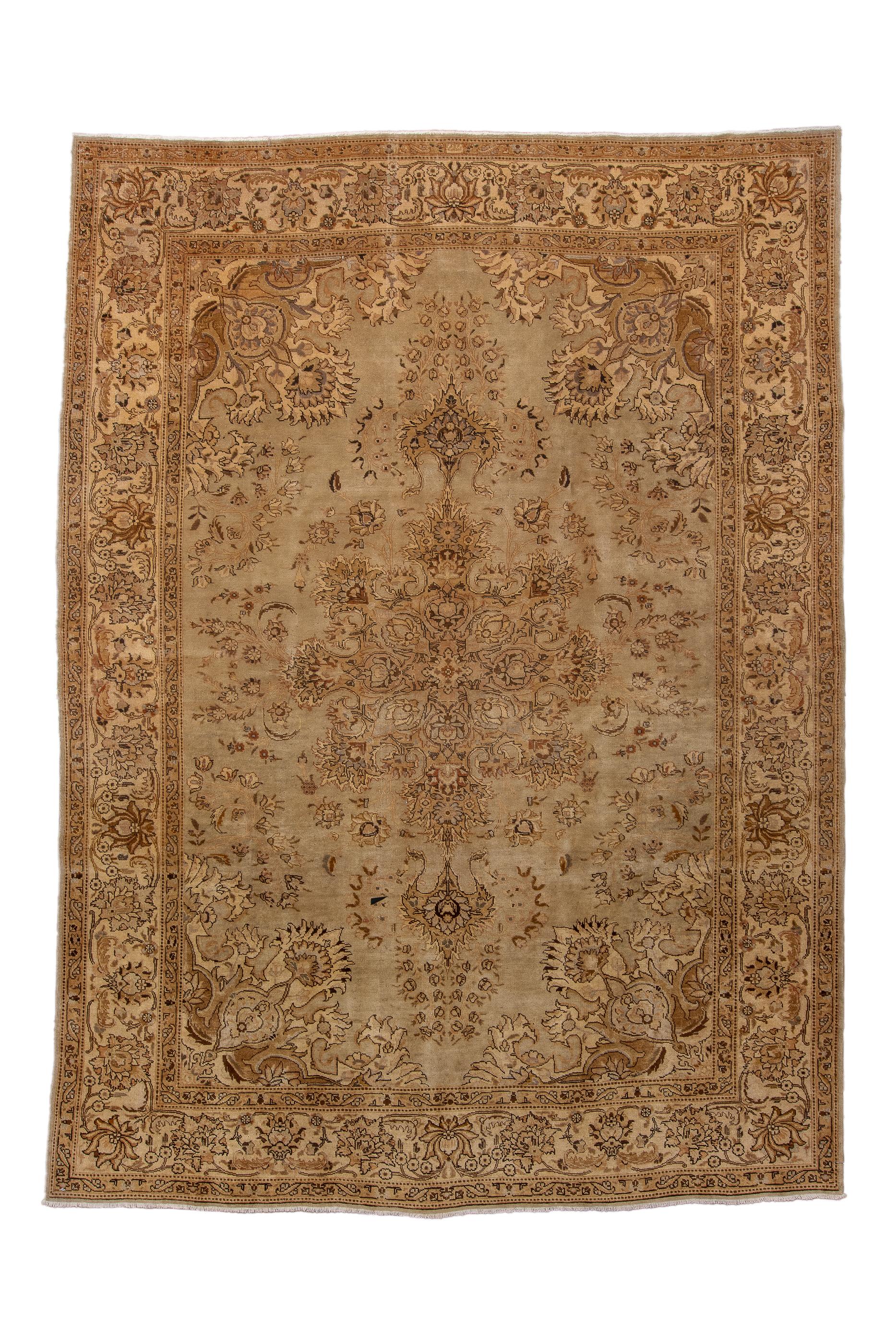 The oatmeal/buff field of this well-woven city carpet shows an elaborate, openwork and palmette medallion with palmette anchor pendants, surrounded by palmettes and detached floral sprays.  Vase and clawing leaf corners.  Straw main border with