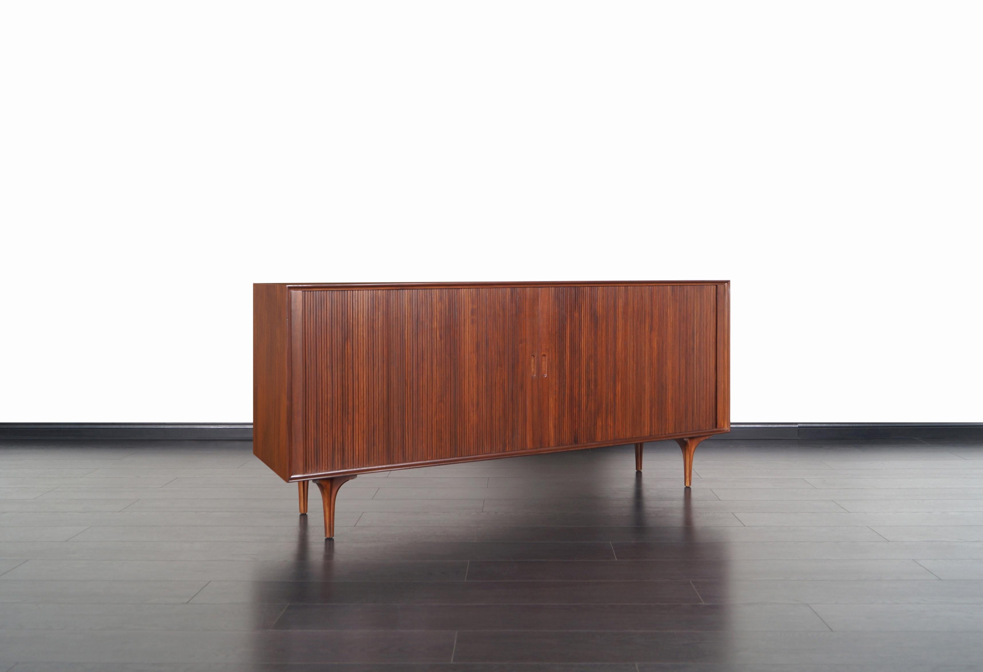 Amazing vintage tambour door credenza designed by Robert Baron for Glenn of California. This exceptional credenza features a well crafted walnut case with two tambour doors that smoothly glide open to reveal a spacious compartments. Equipped with