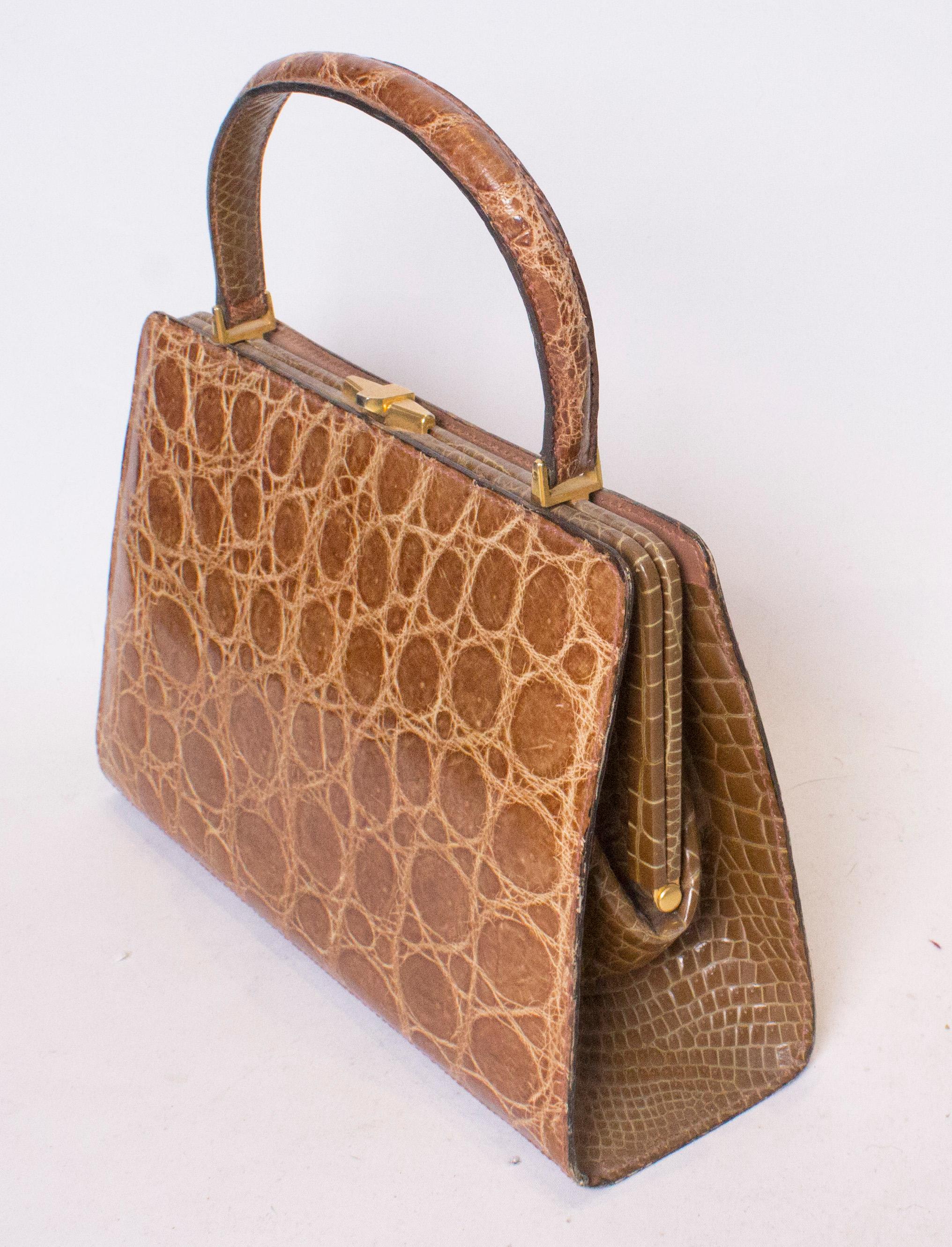 A chic biscuit colour top handle vintage crocodile handbag.
The bag has a central clasp and internally there are two pouch pockets and one zip pocket.
The bag has four stud feet. Measurements: width 11'', height 7 1/2'', depth 3 1/2''.