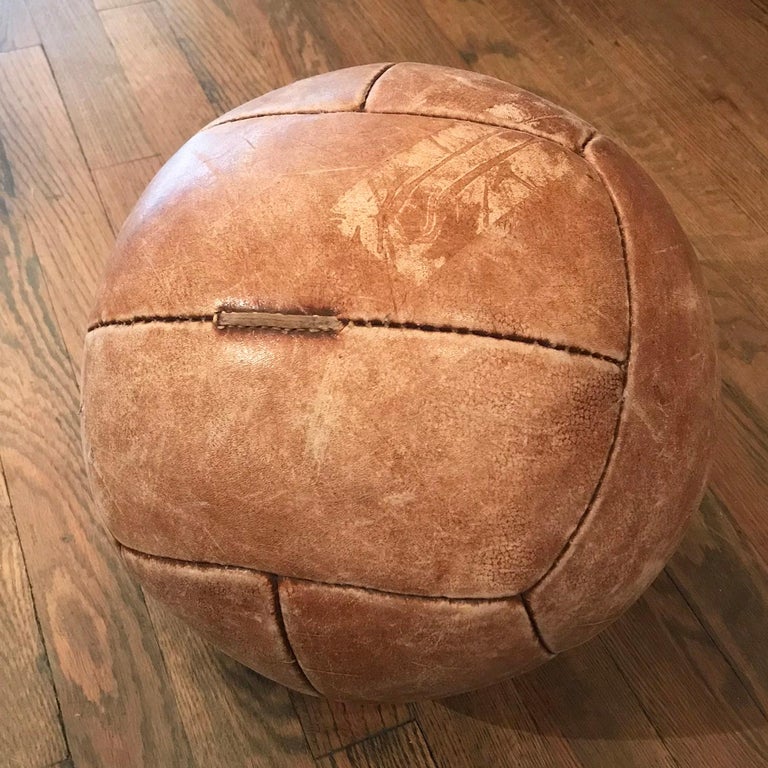 Vintage medicine ball for upper body strength training features a tan leather hide with its original well-worn patina.