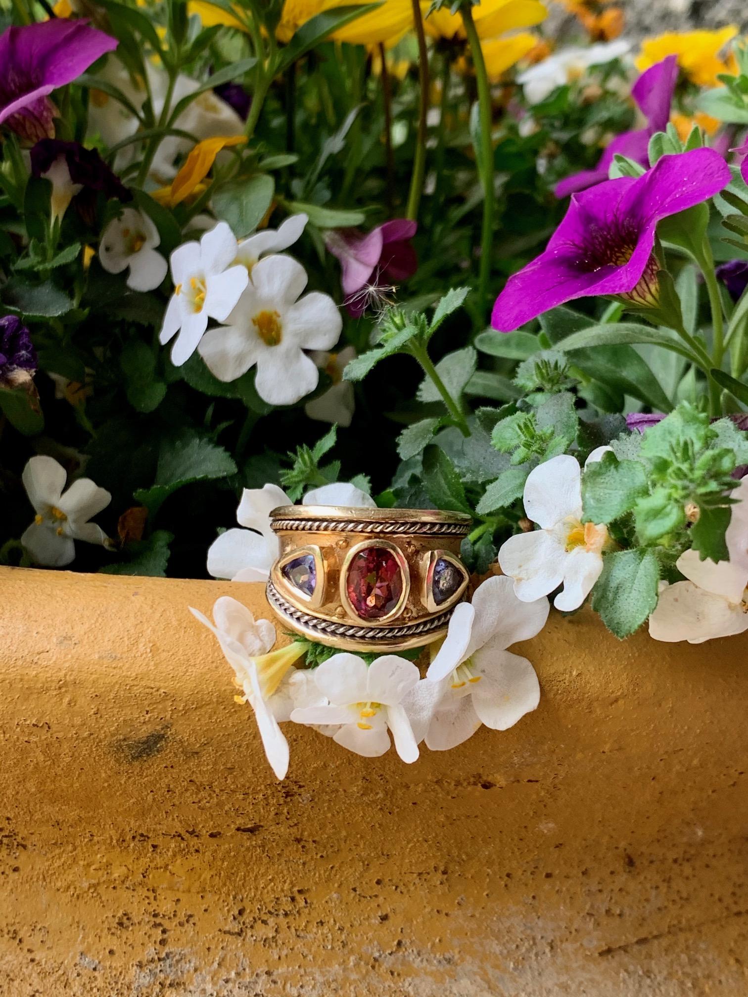 This handsome ring has a large oval Pink Tourmaline and two Tanzanite stones.  The setting is strong and makes quite a statement.  The ring looks very regal.  

It is stamped 14k.  

Size US 9 - this ring is resizable but vendor does not offer