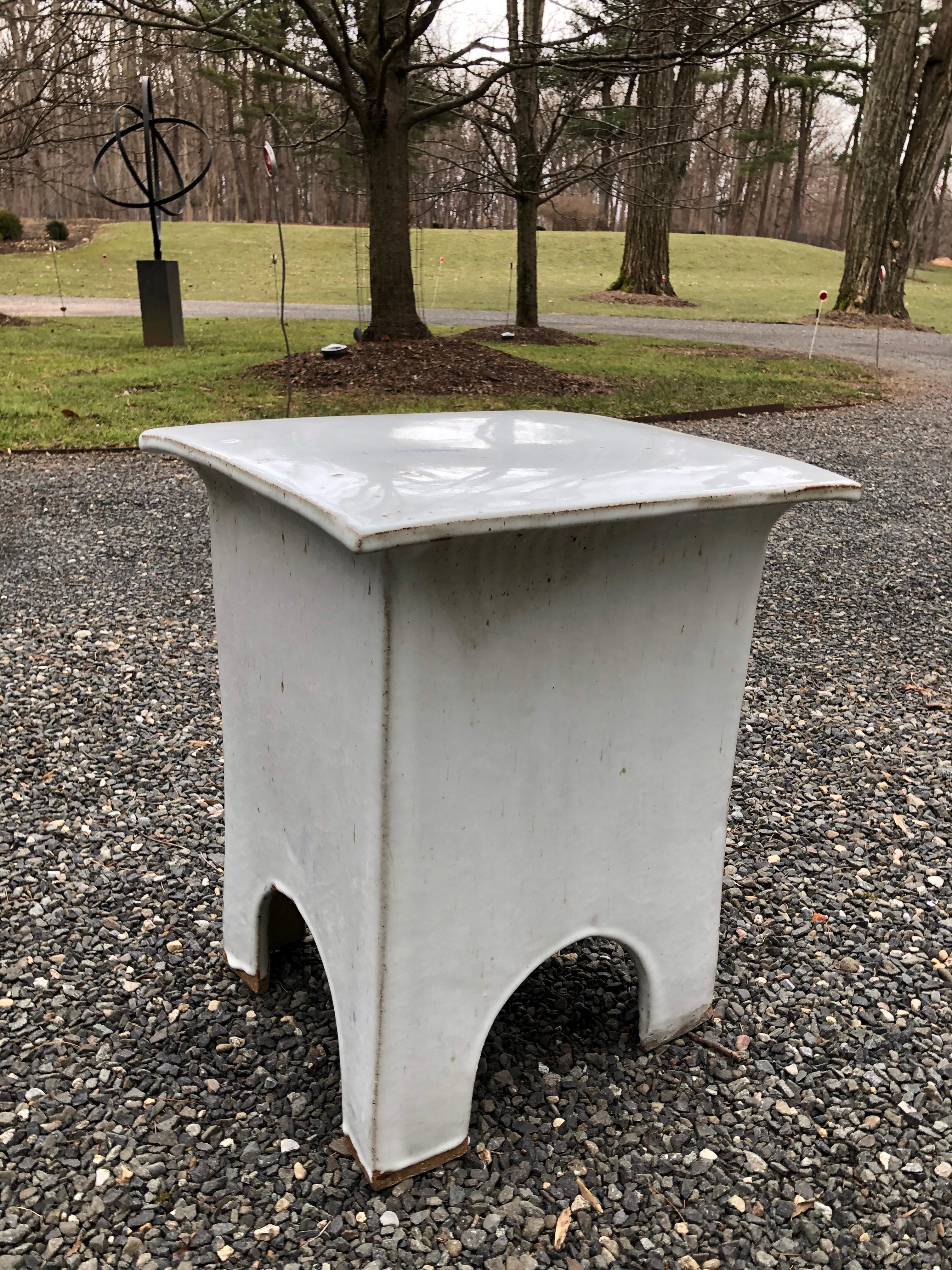 A Tariki Studio stool or end table having white glaze and simple lines.  There is a small spot/discoloration on the top, but this was in the glazing and is original to the piece.  
  