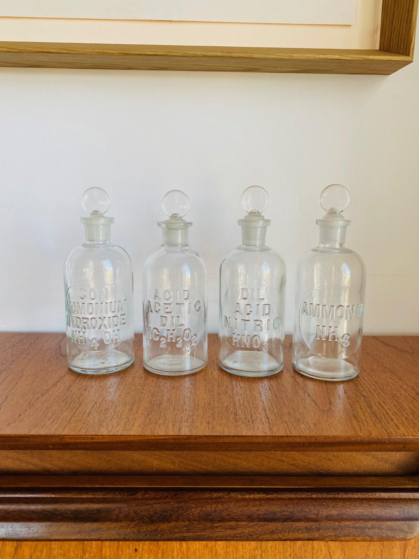 Vintage set de 4 bouteilles d'apothicaire vintage avec bouchons et embossé.  Classiques et uniques, ces magnifiques bouteilles scintillent dans le verre vintage avec beauté et form A.  La forme classique de la bouteille et du bouchon ajoute une