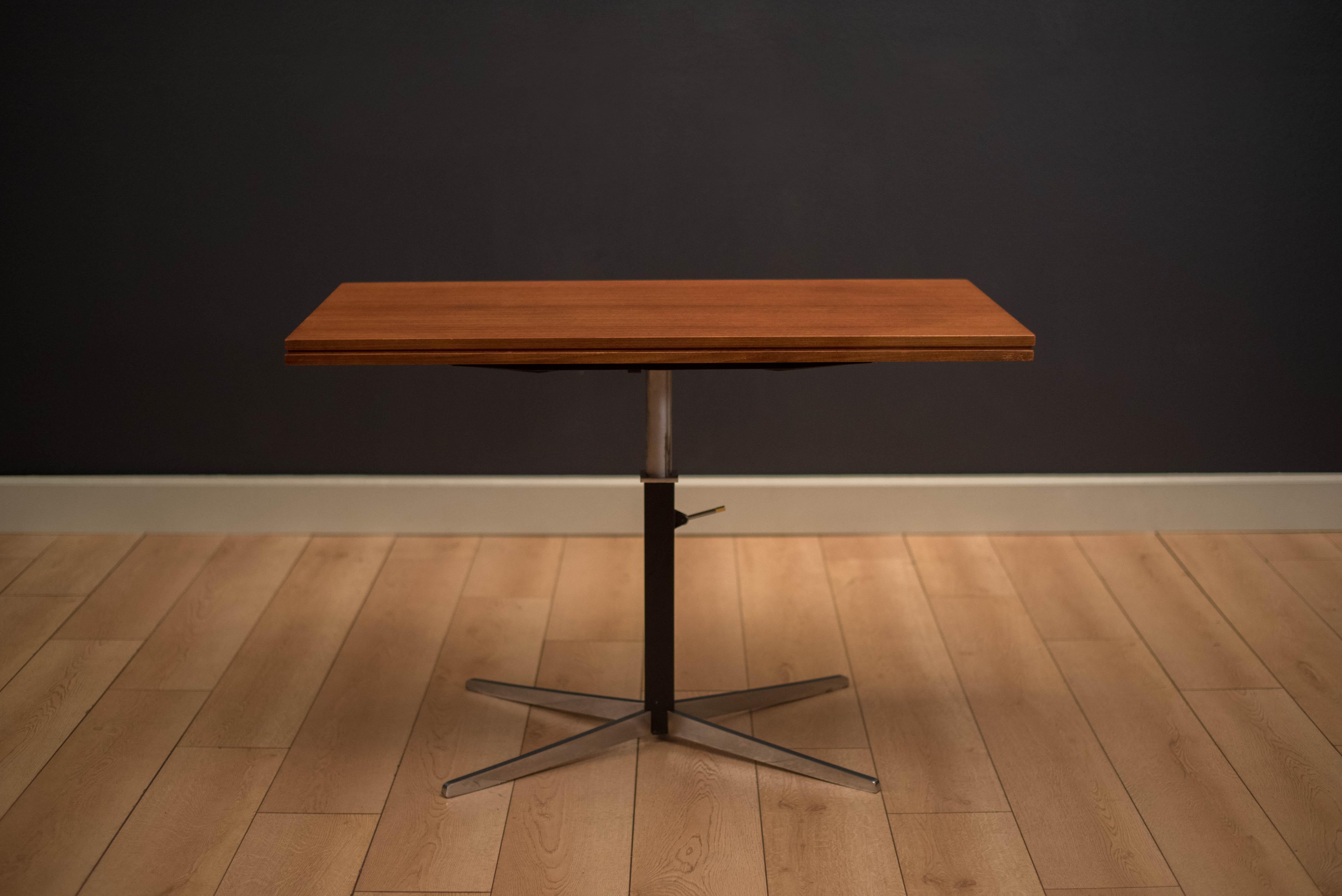 Mid century adjustable elevator flip top table designed by J.M. Thomas for Wilhelm Renz. This versatile piece can convert from a coffee table to a dining table by adjusting the height of the aluminum base. Teak finished table top slides over to