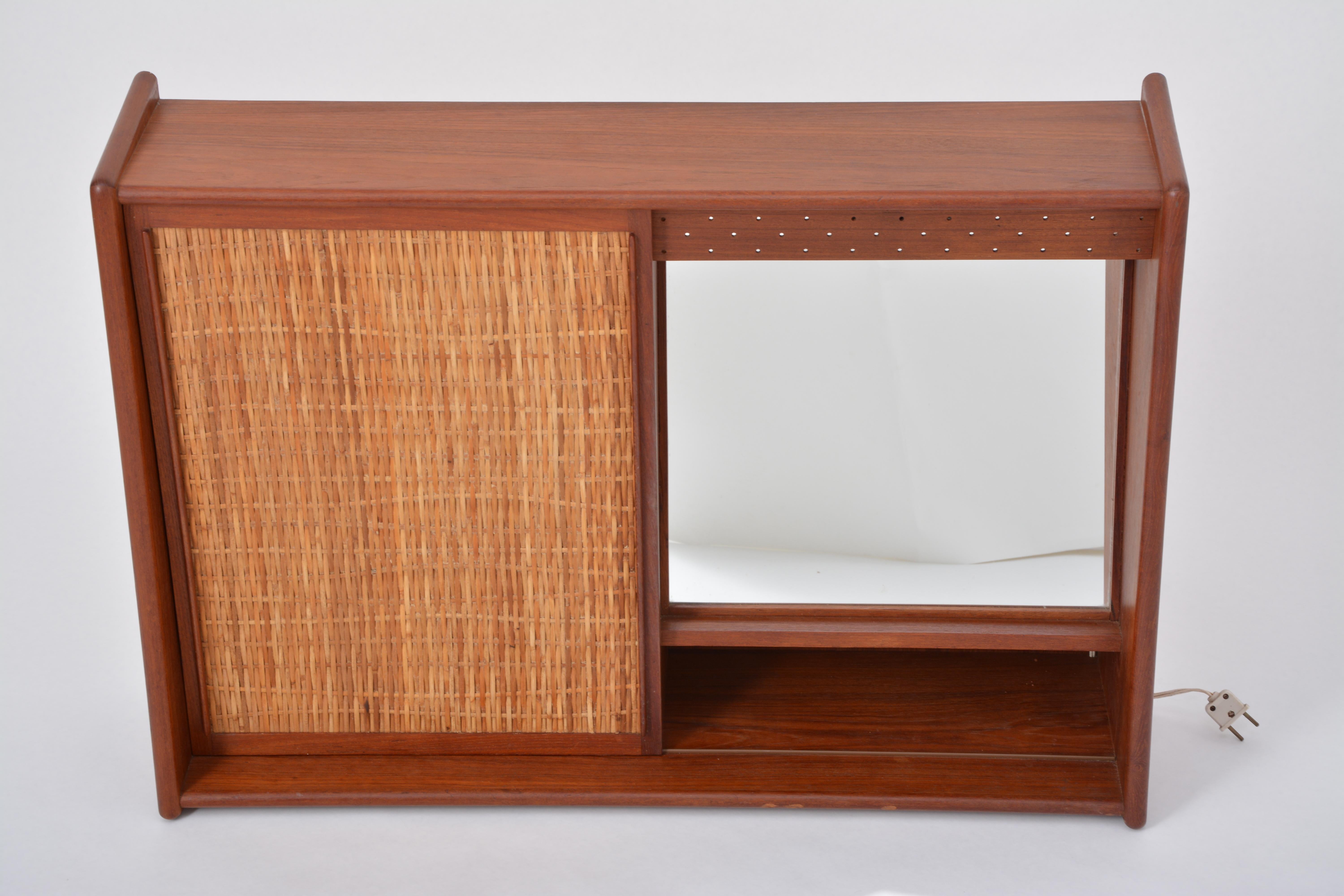 Danish Mid-Century Modern Teak bathroom cabinet with sliding door and mirror

This small bathroom cabinet is made of teak wood and was produced in Denmark, probably in the 1960s. It has one sliding door with a beautiful rattan front. The door covers