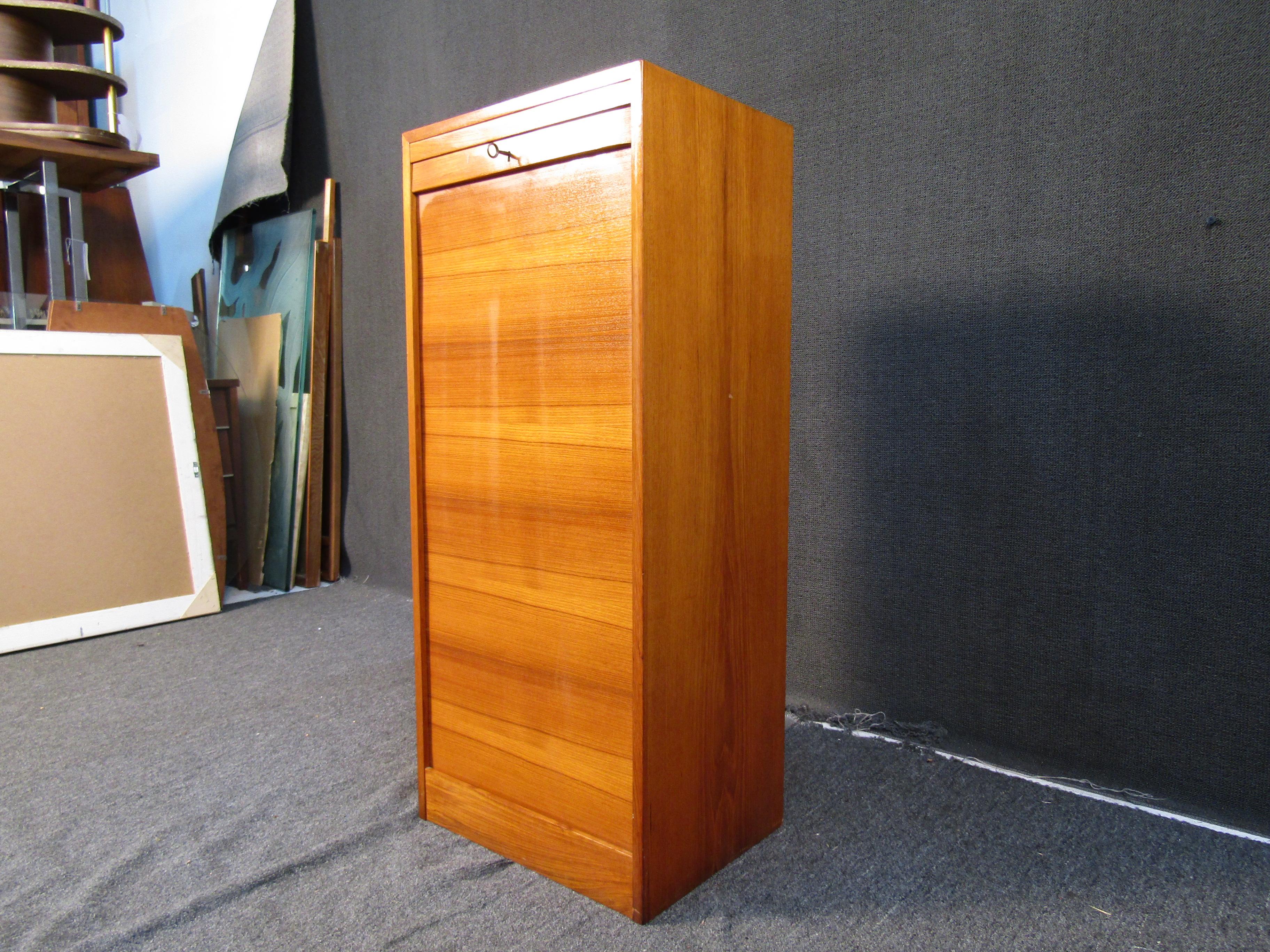 This Mid-Century Modern campaign filing cabinet offers plenty of organization with multiple drawers that are hidden behind a locking door. Rich teak woodgrain completes this cabinet and makes it a stylish addition to any home or office. Please