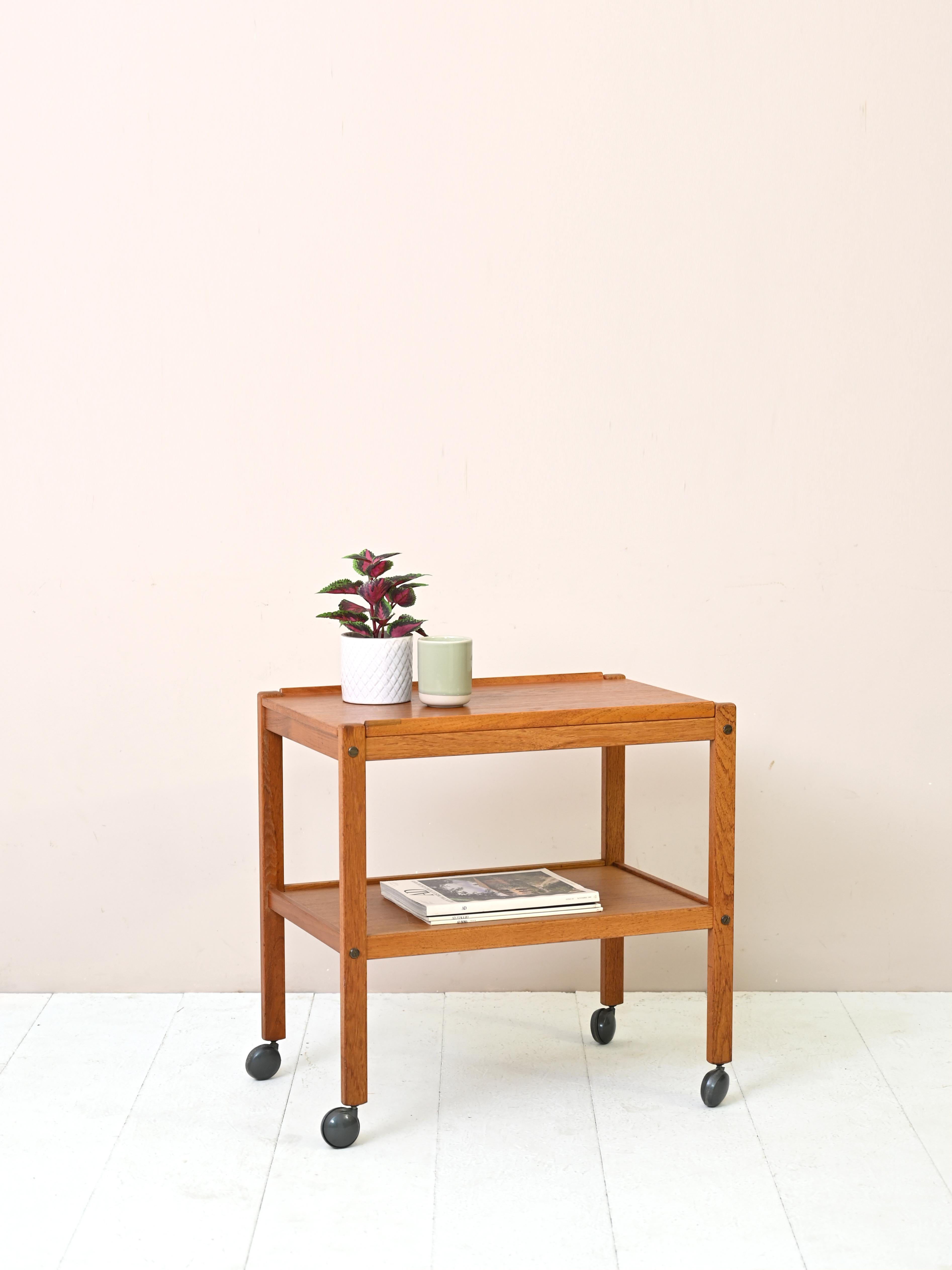 Coffee table with wheels of 1960s Scandinavian manufacture.

The simple, linear structure features two shelves; the top one can be removed and used as a supporting tray.
Ideal for use as a sofa table thanks to its small size and the
practical