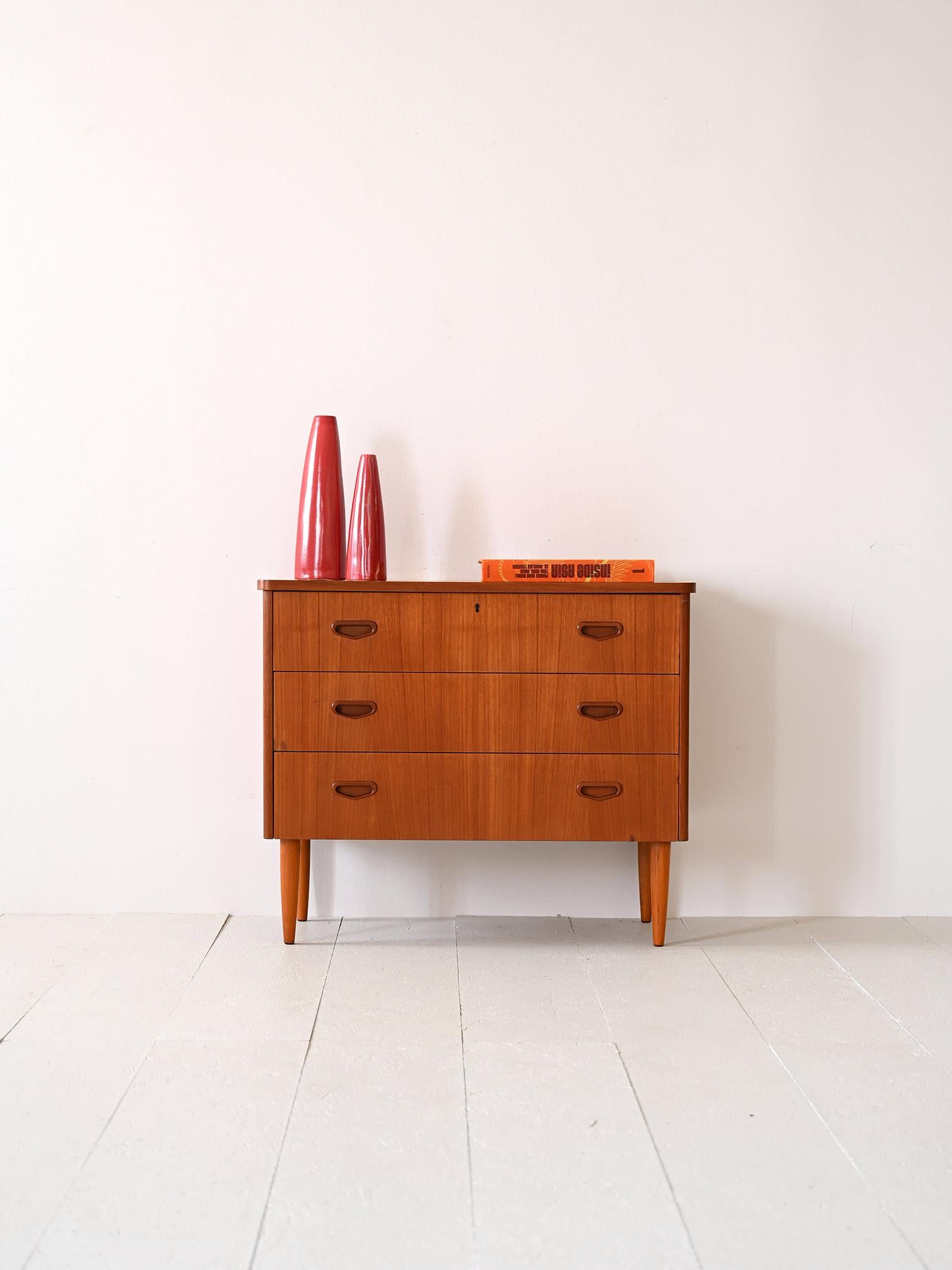 Vintage teak chest of drawers of Swedish manufacture.
Scandinavian cabinet with 3 drawers, the first of which has a lock.
A modern piece characterized by square lines and the coppery color of teak wood.
The long tapered legs slender the frame and