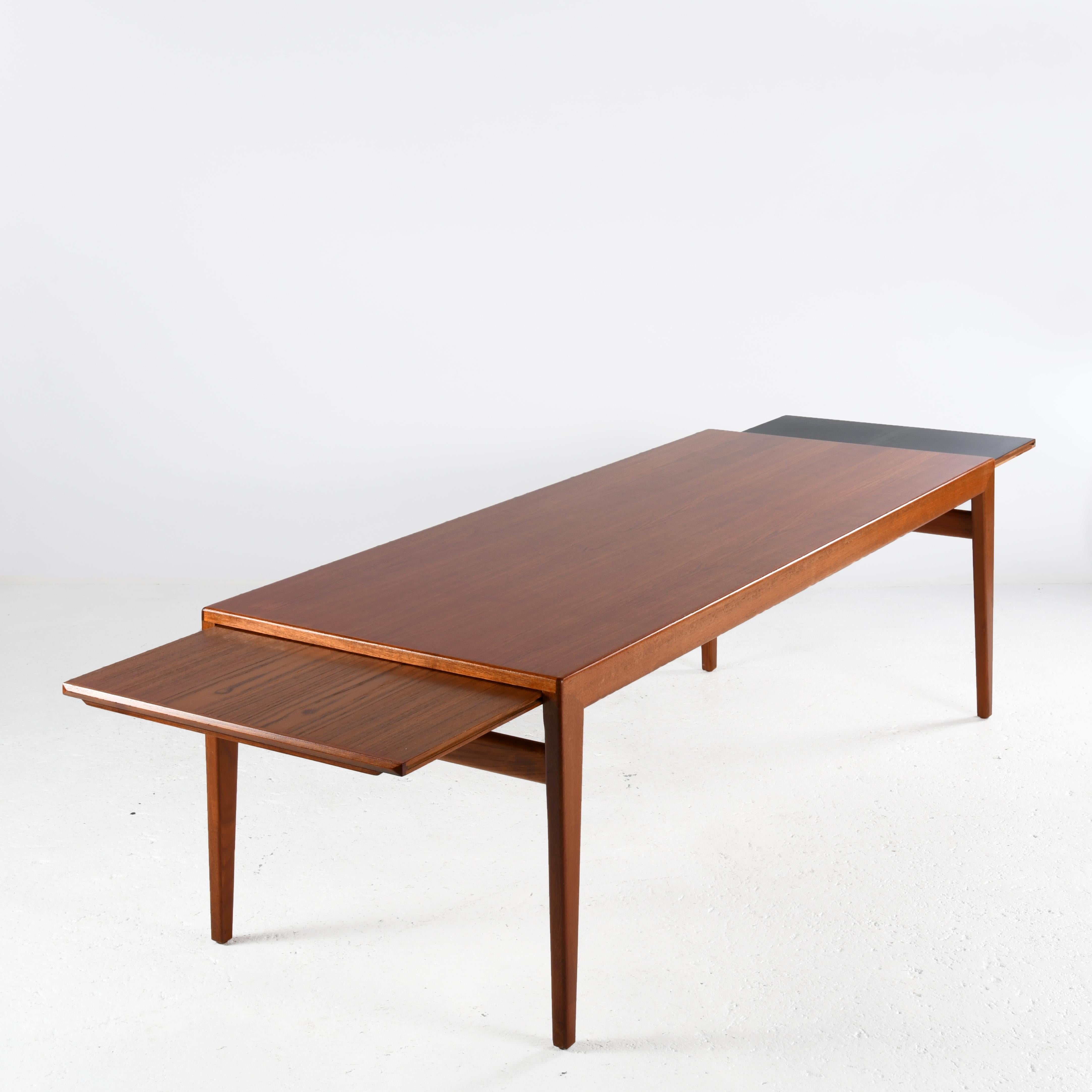 Large teak wood coffee table from the 1960s, designed by Johannes Andersen (1903-1991). Two retractable extensions under the top at either end, one in teak veneer, the other in black laminate veneer. The teak tops are protected by a satin varnish to