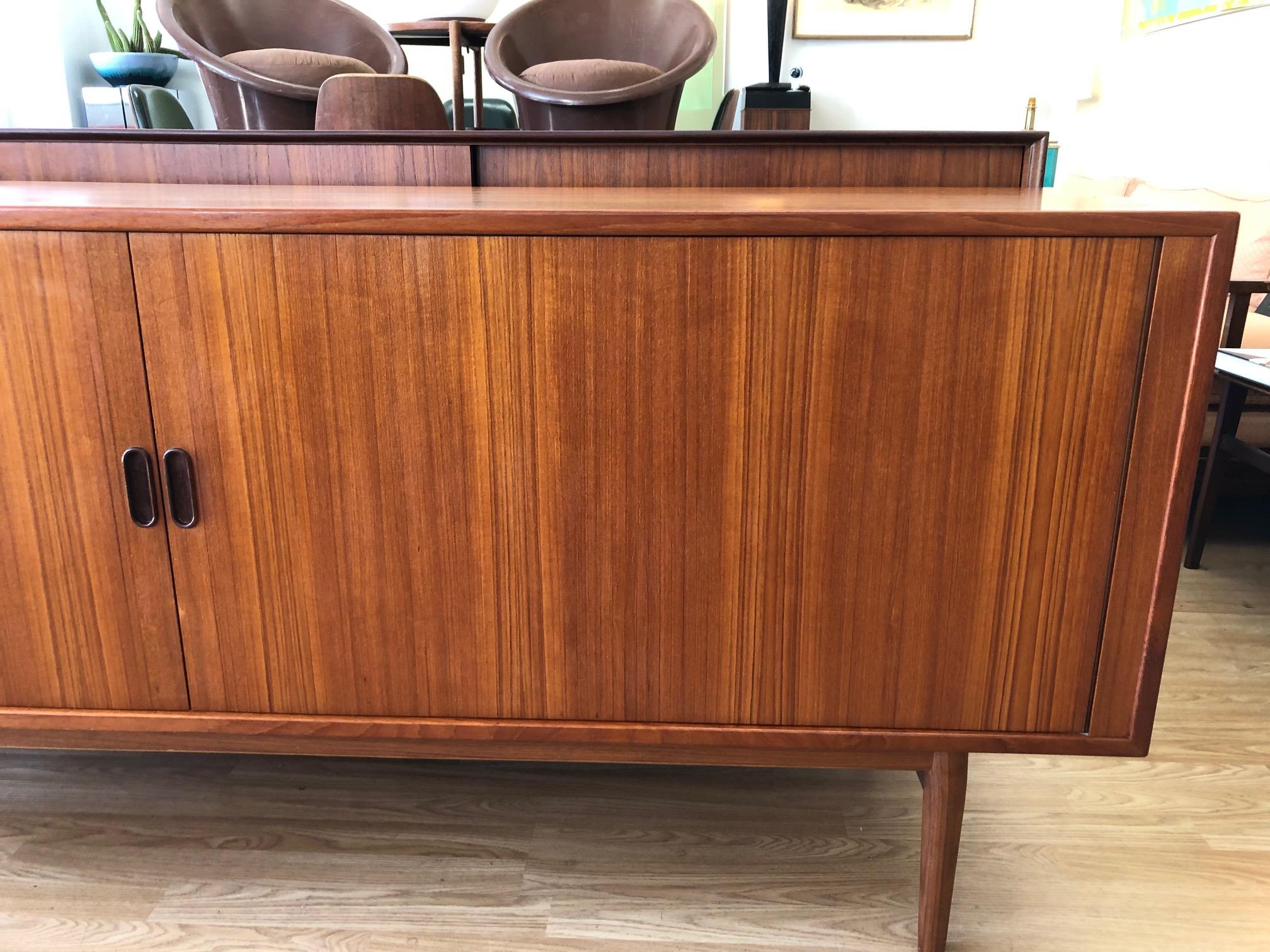 This beautifully crafted vintage credenza by Arne Vodder is in overall good condition. Teak wood. Sliding tambour doors. Interior adjustable shelving and two drawers. Label inside. (See photos),
circa 1960s, Denmark.
Dimensions:
31.5