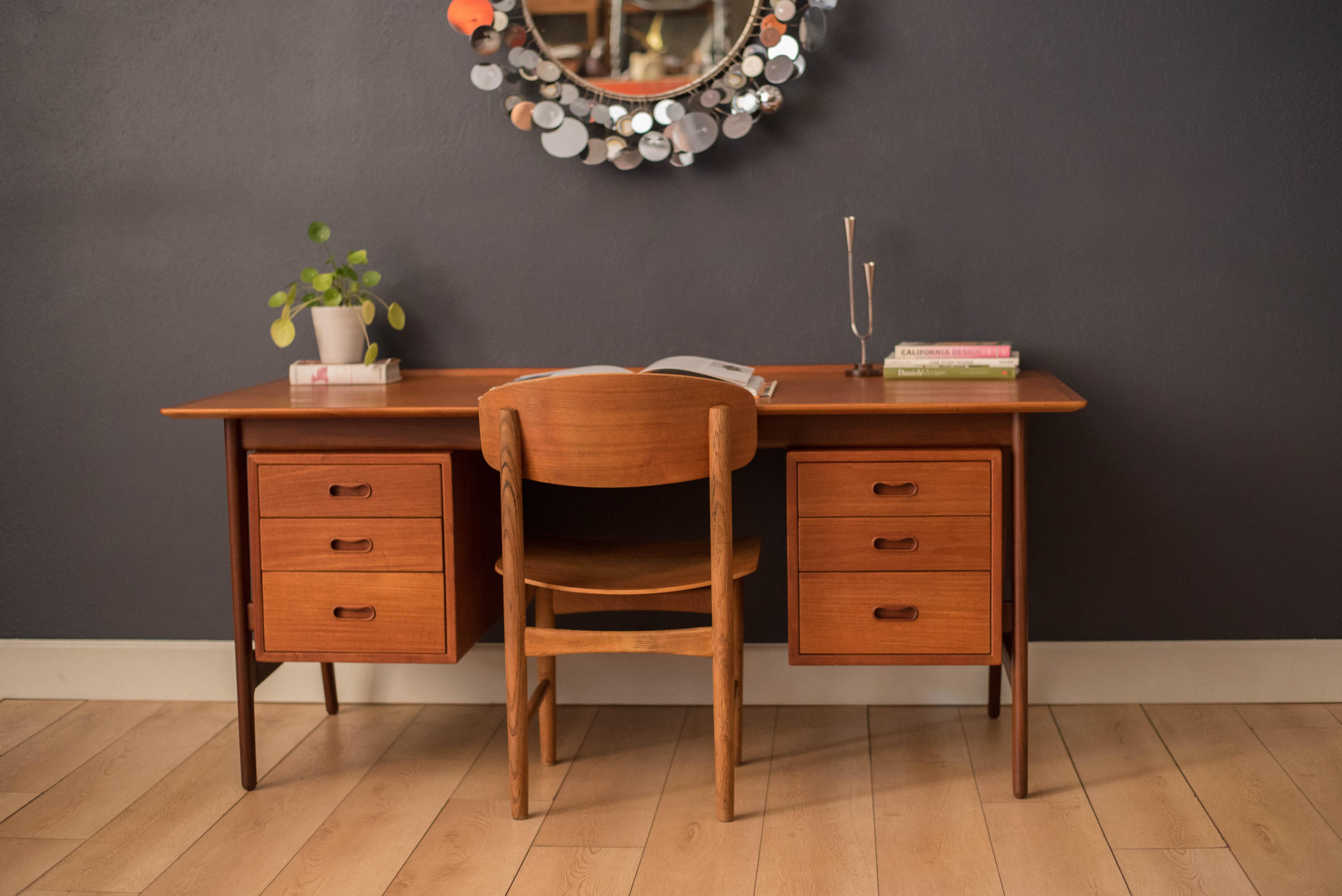 Mid-Century Modern executive desk in teak designed by Arne Vodder for Vamo Sonderborg, Denmark. Features a unique floating top with a raised lip edge and external supporting legs. This piece includes six dovetailed drawers accented with solid wood