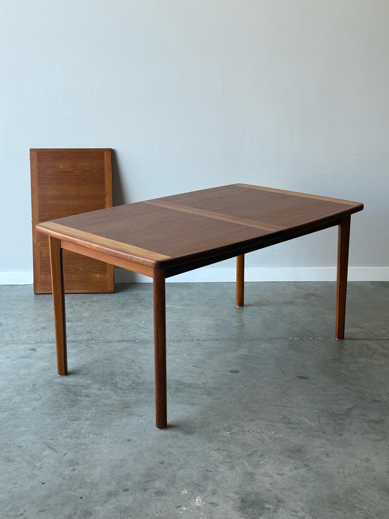 Vintage teak dining table, made in Denmark. Equipped with one additional leaf. This dining table has several unique design features. Rectangular in shape, yet rounded corners and sides. The lighter color banding on the ends and middle is seldom seen