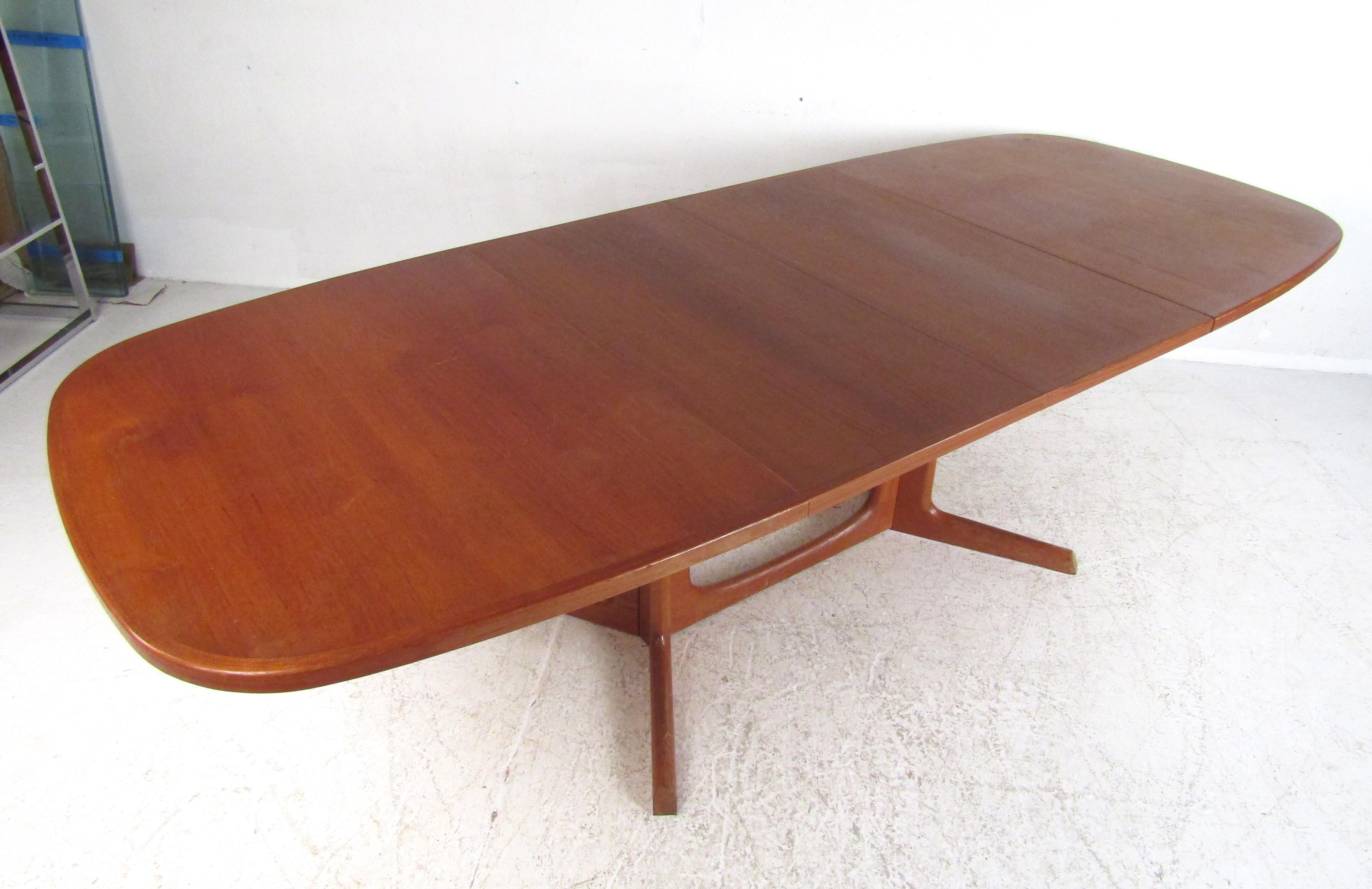 Exquisite midcentury Danish modern dining table that includes two leaves allowing this table to go from 63.5 inches wide to 102 inches wide. A well-made Danish design stamped by the manufacturer with an extremely rich vintage teak finish. The smooth
