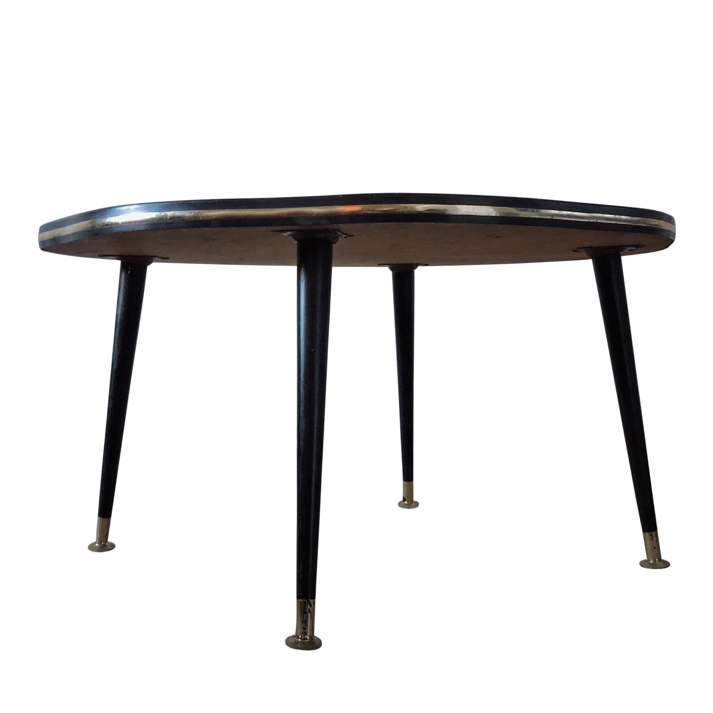 This vintage coffee table with a teak Formica top has a metal rim and feet, featuring black tapered legs. It was manufactured in the 1960s.