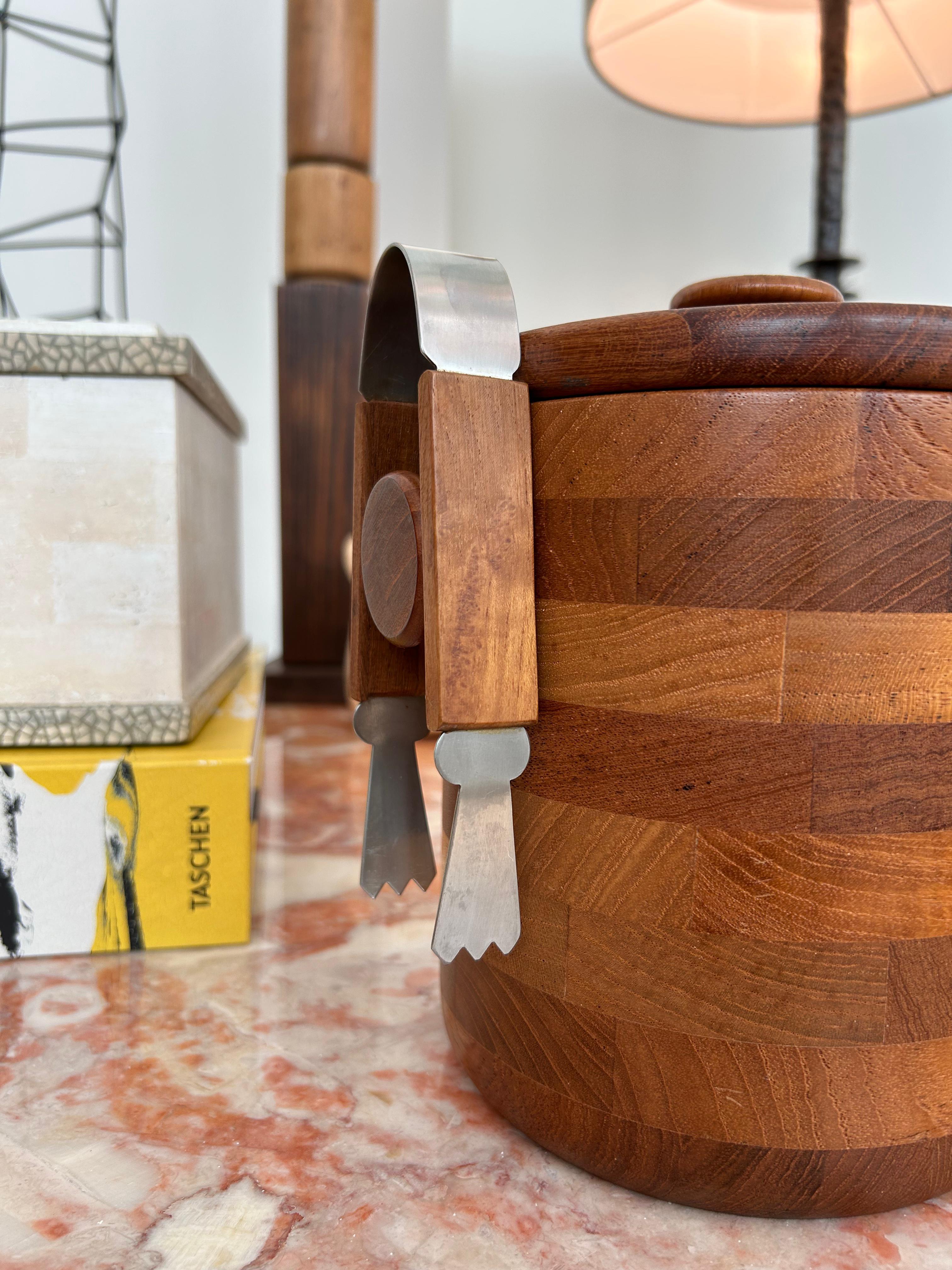 Un magnifique seau à glace vintage de Viners of Sheffield, datant des années 1960. Fabriquée en bois de teck, cette pièce présente un design rayé bicolore saisissant qui ajoute un intérêt visuel et de l'élégance à n'importe quel bar ou espace de