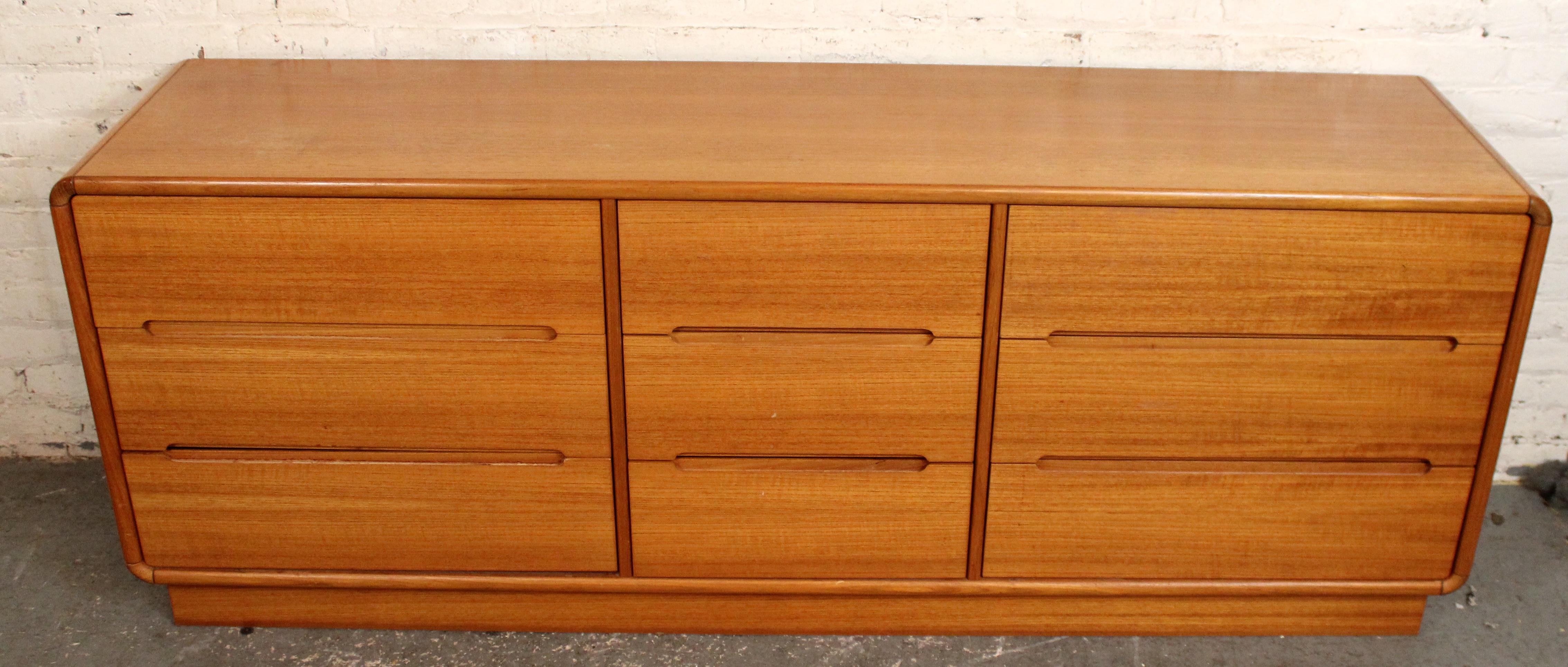 An elegant mid‑century modern lowboy crafted by Sun Cabinet, this piece showcases a warm teak veneer and refined, minimalist design. Featuring a low-profile silhouette, it offers a combination of spacious drawers with clean‐lined fronts and discreet