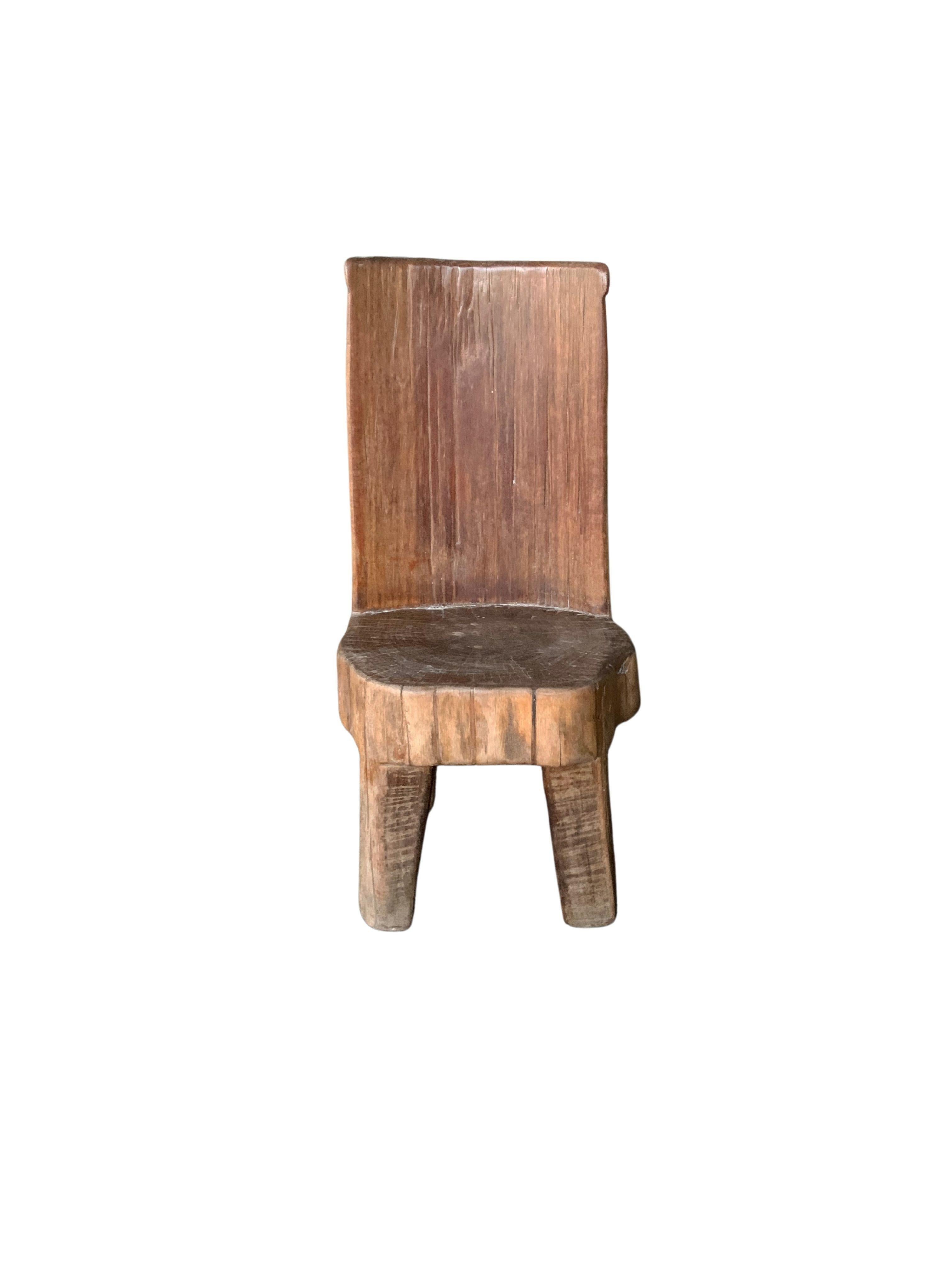 Ce mini tabouret de la fin du XXe siècle présente une belle texture de bois, fabriquée à partir d'un bloc de teck massif. Ces tabourets étaient utilisés sur l'île de Madura par les travailleurs des plantations de tabac pour couper et tailler le