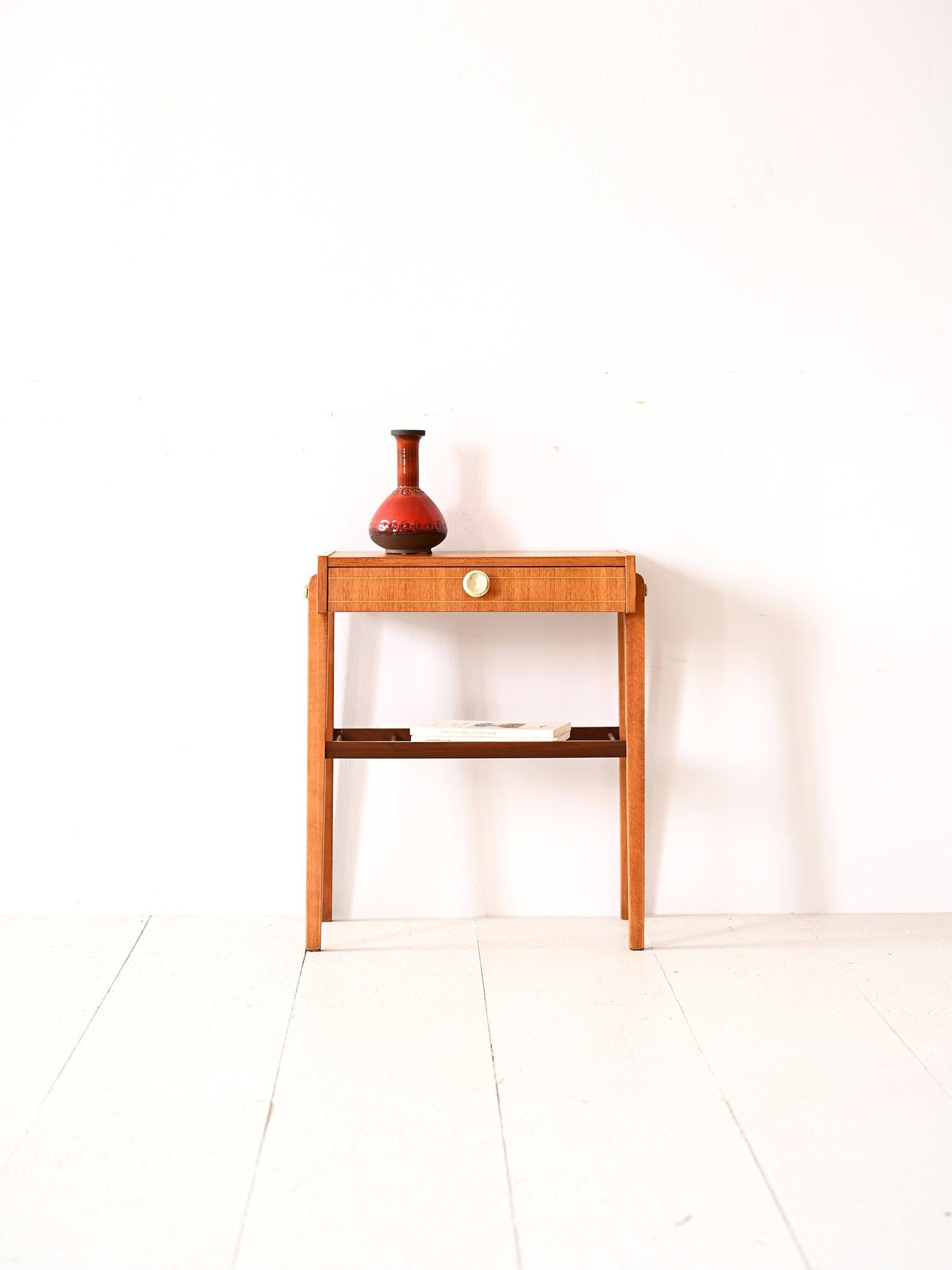 Side table with drawer and magazine rack top.

The style of this bedside table perfectly traces mid-century taste and design that combines a love of simple lines without forgetting attention to detail. 
Consisting of a teak top and beech legs, it
