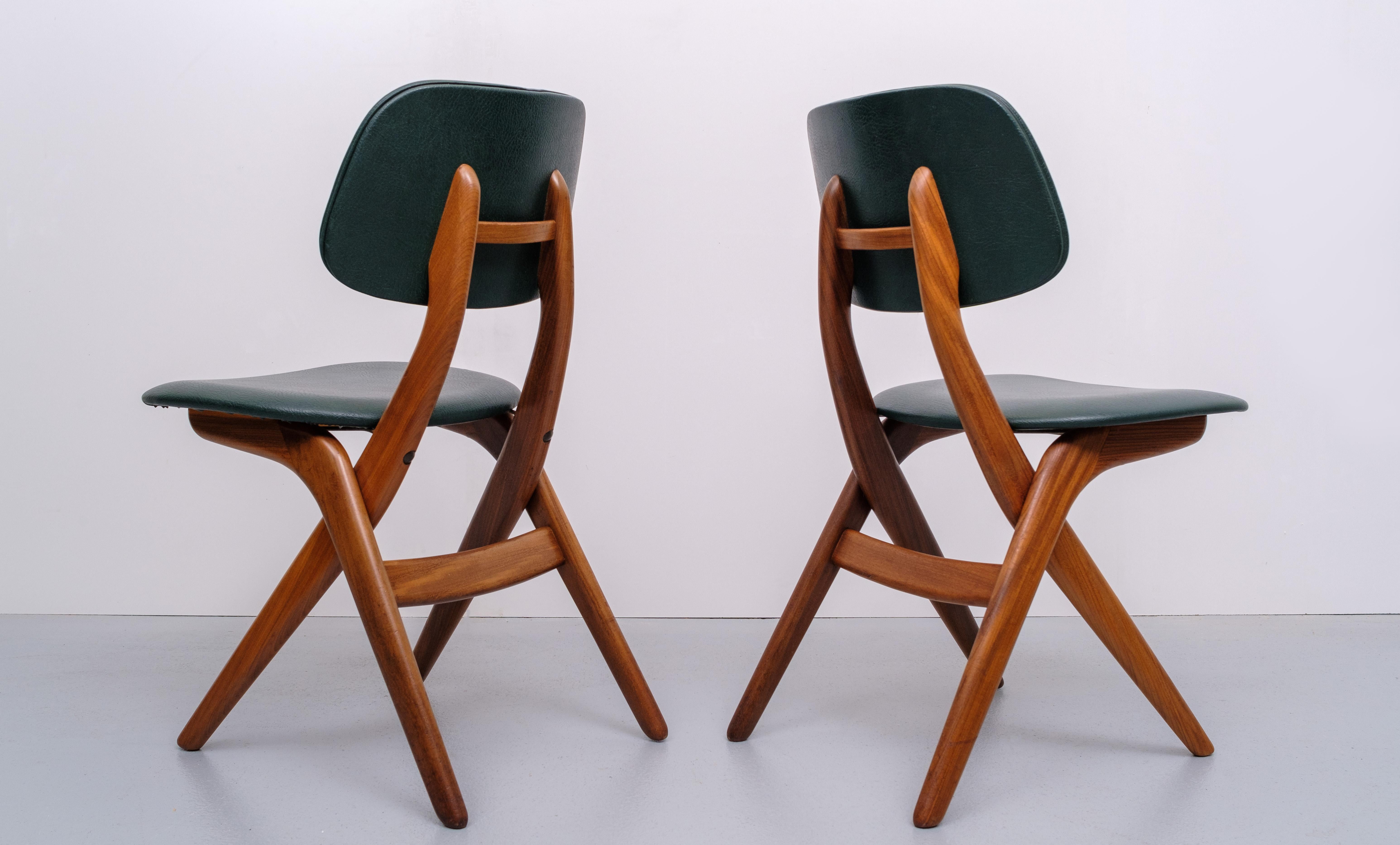 Set of 2 dining chairs, designed by Louis van Teeffelen for Webe in Netherlands. The model features front legs which move up into the backrest while crossing the rear legs - this 'crossed wood' design was a specialty of Van Teeffelen. Frame is made