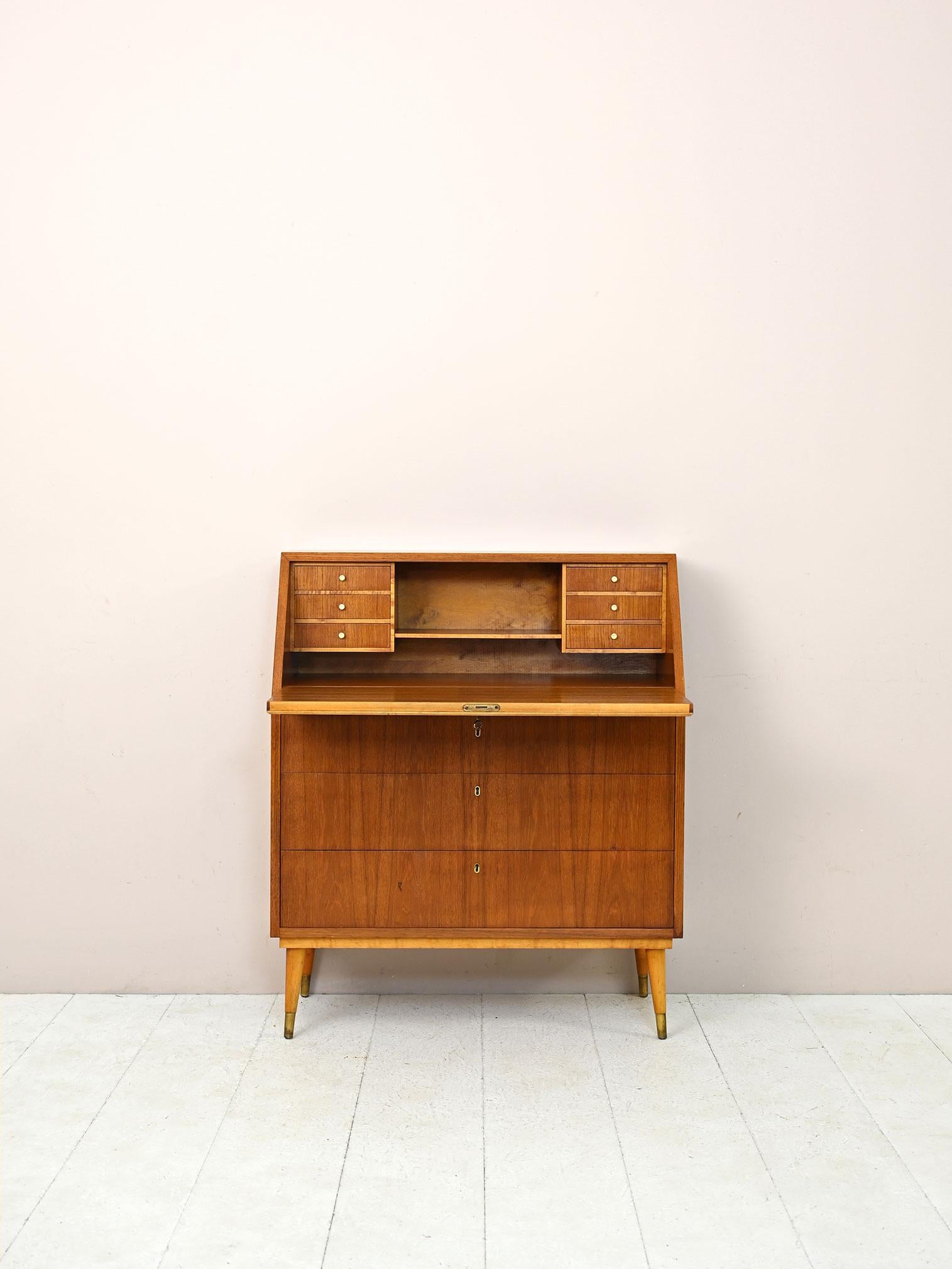 Scandinavian chest of drawers with fliptop.

A retro-flavored piece of furniture that traces midcentury taste.
Consisting of a teak frame with 3 drawers and a flap inside which are small drawers and a small shelf. 
Ideal for recreating a smart
