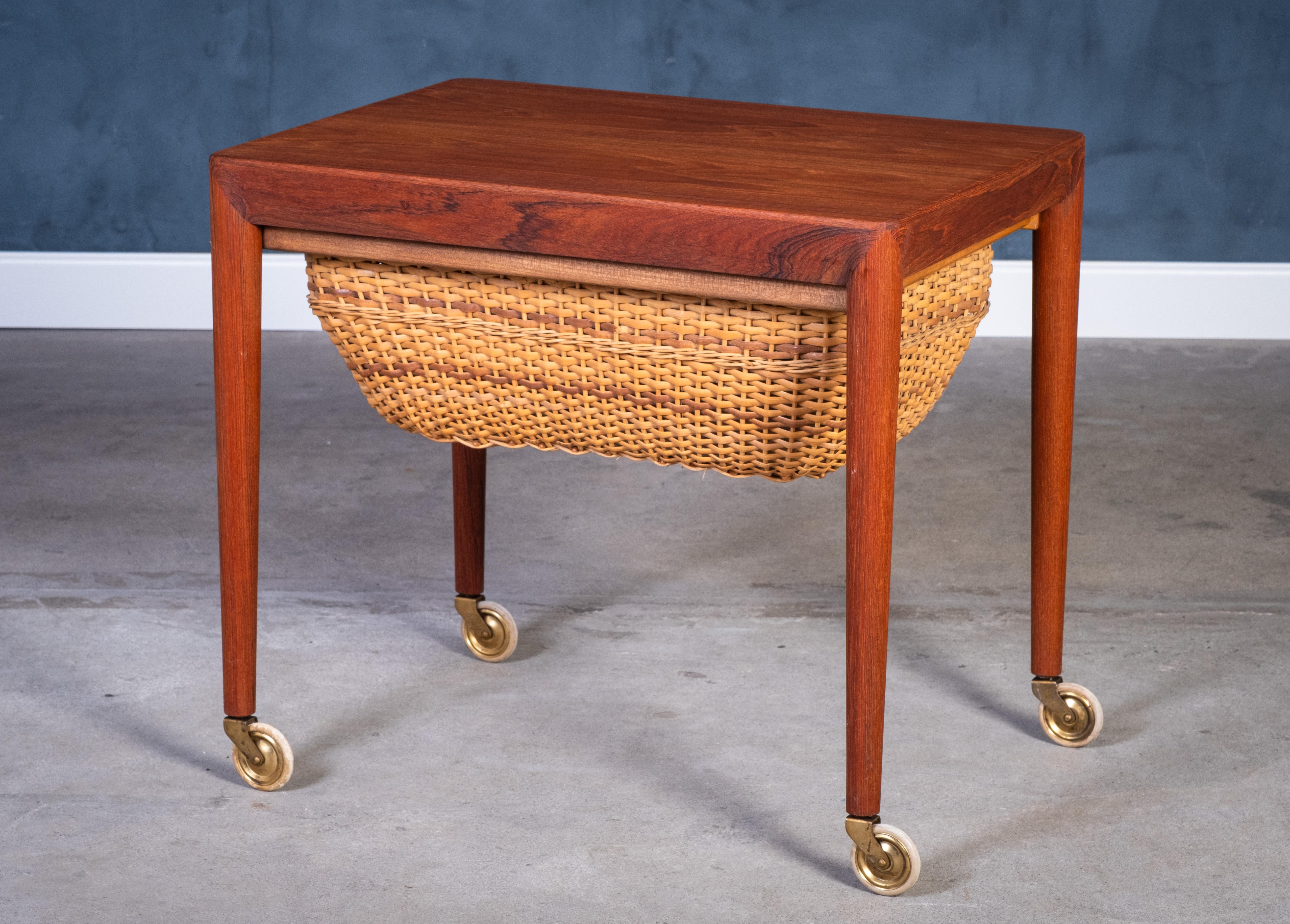 Esta elegante mesa de costura fue diseñada por Erik Severin Hansen y producida por Haslev Møbelsnedkeri en Dinamarca durante la década de 1960. Fabricada en teca, la pieza ejemplifica la refinada artesanía y la estética minimalista características
