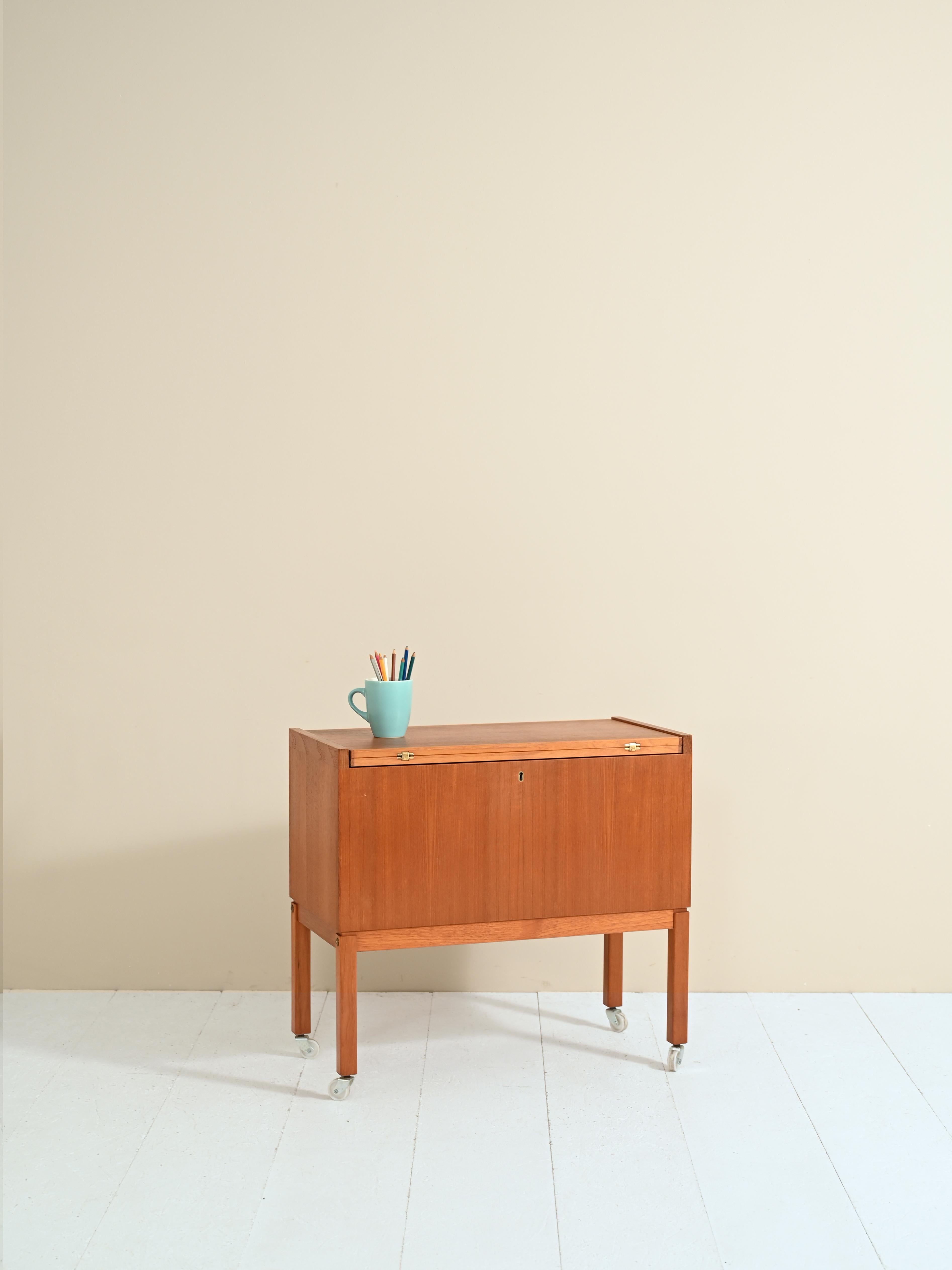 Teak wood sewing table, the production is Scandinavian vintage from the 1950s.

The table has a flip top that turns the cart into a convenient 70 x 70cm square table top.
Hidden under the top is the capacious compartment originally used to hold