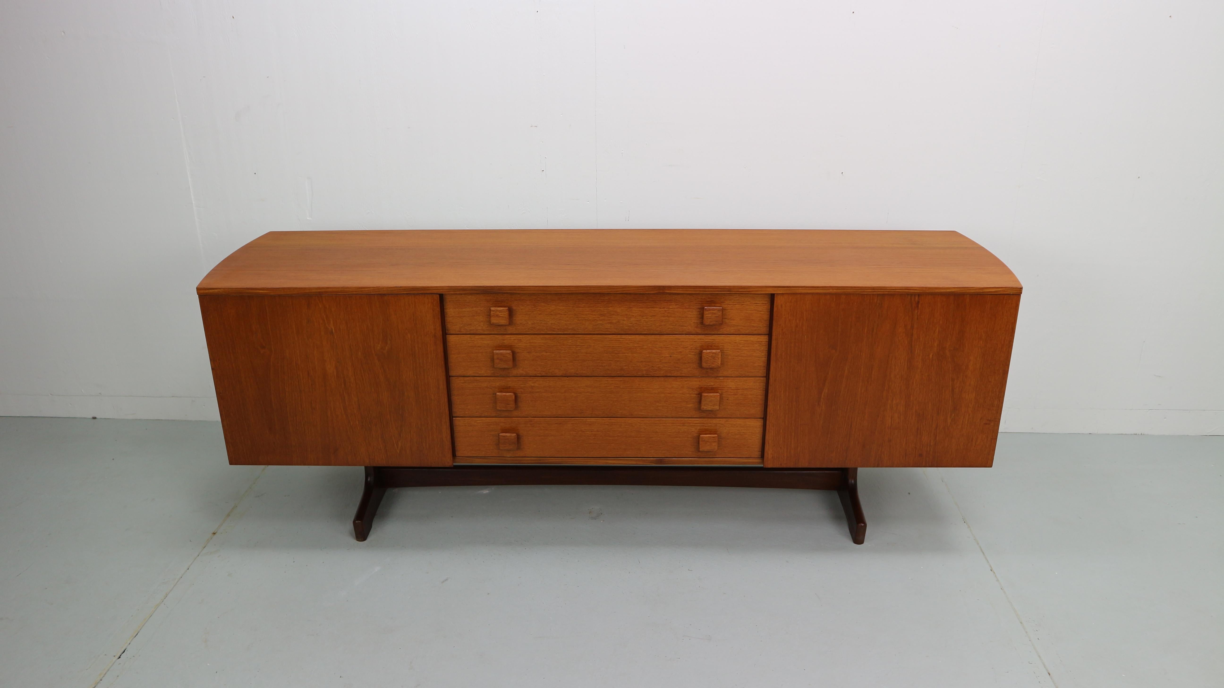 Midcentury sideboard with curves sides in teak wood. Four drawers and 2 doors with shelf's behind it. Refurbished and refinished in hardwax.