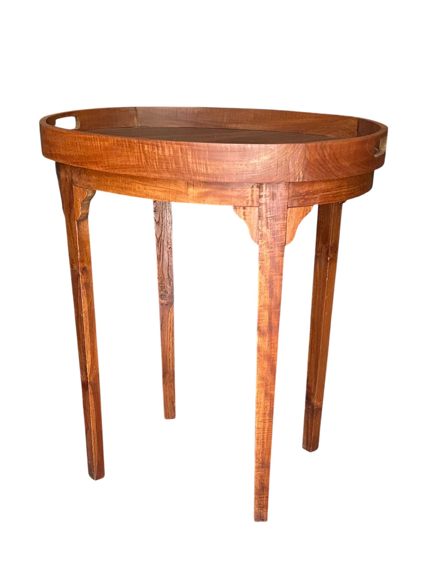 Table d'appoint vintage en teck à plateau pour majordome.

Cette table plateau vintage en bois de teck épuré repose sur quatre pieds fuselés.  La base simple et solide supporte un plateau ovale amovible avec des poignées découpées.  État : très bon