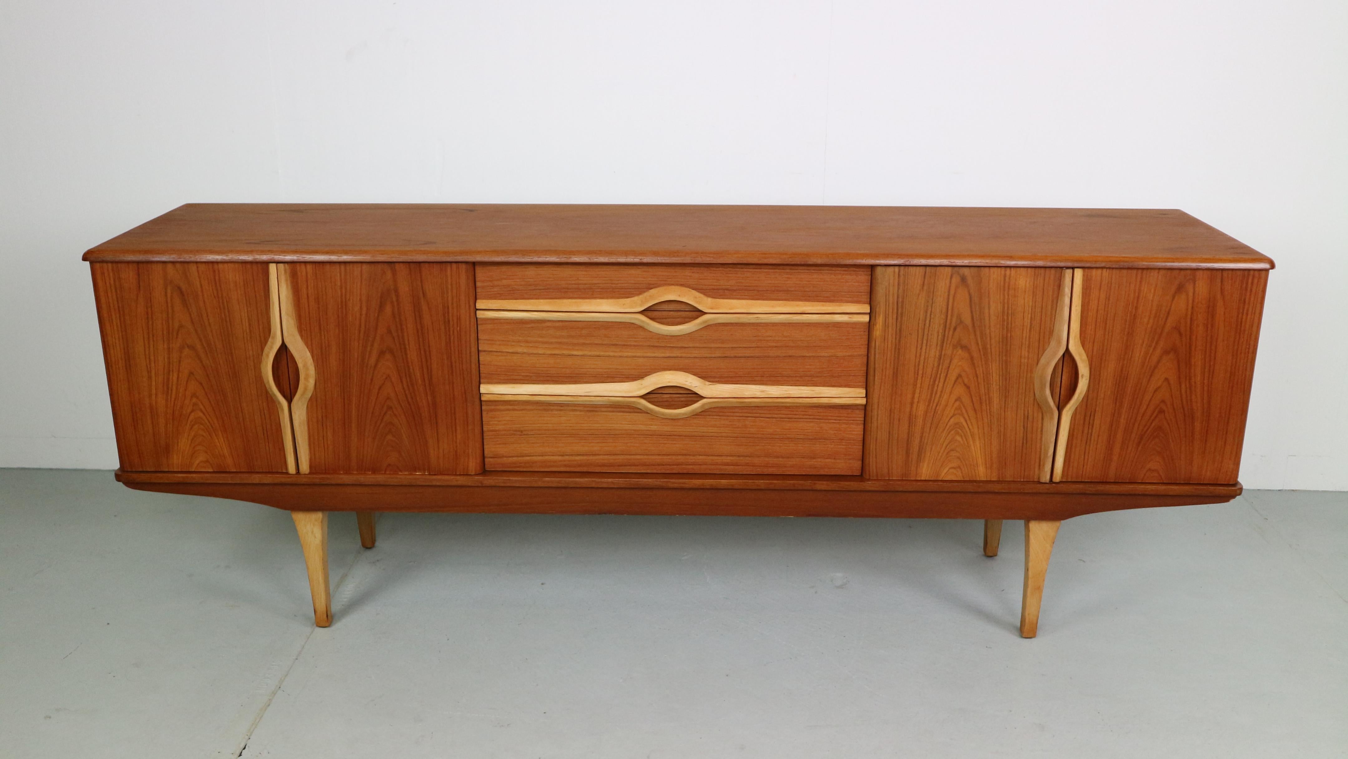 A beautiful design piece by Stonehill. This two-tone teak sideboard has three central drawers, two compartments with folding doors either side all accented by decorative long thin pale teak handles giving the piece a unique look.