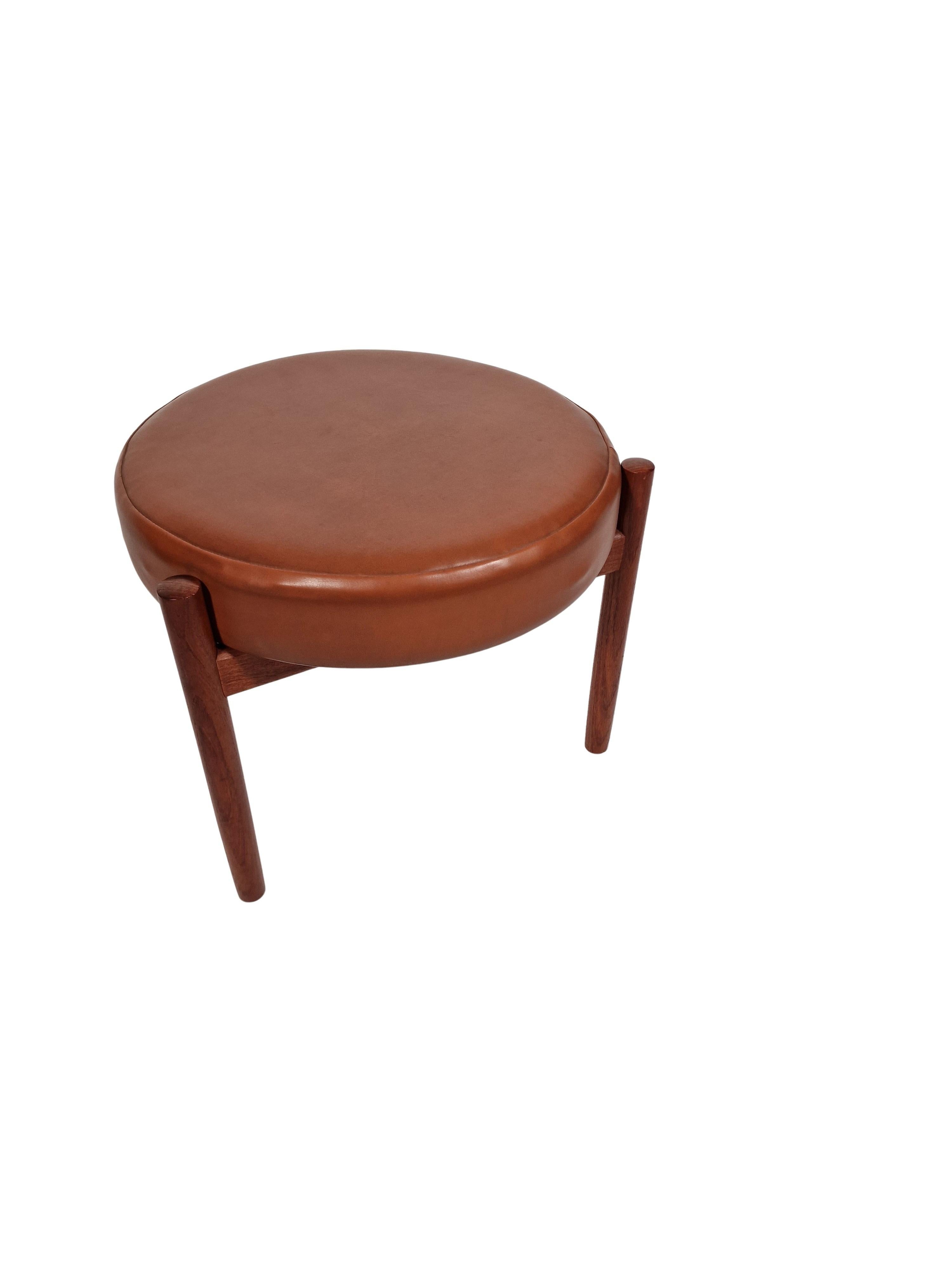 Very nice decorative stool made by the Danish designer Hugo Frandsen, for the Danish furniture producer Spøttrup Mobler in the 1960s. 

The stool has a tripod structure in high quality solid teak and a round seat covered with light brown leather.