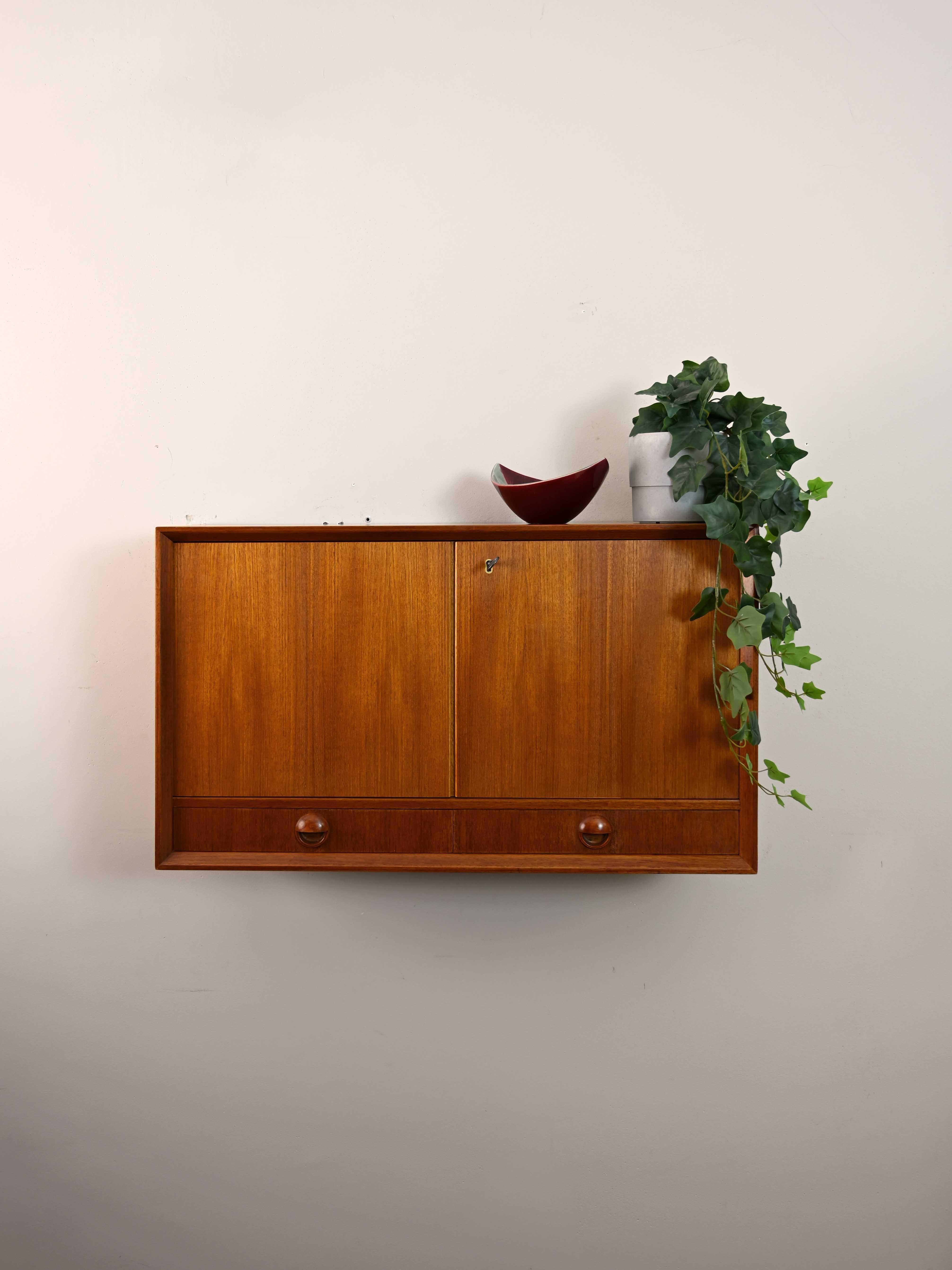 Scandinavian modernist cabinet.

A small furniture piece, ideal as a bathroom cabinet. The frame is teak with lockable hinged doors, and there are two small drawers with a carved wooden handle.

Good condition. It may show some signs of time.