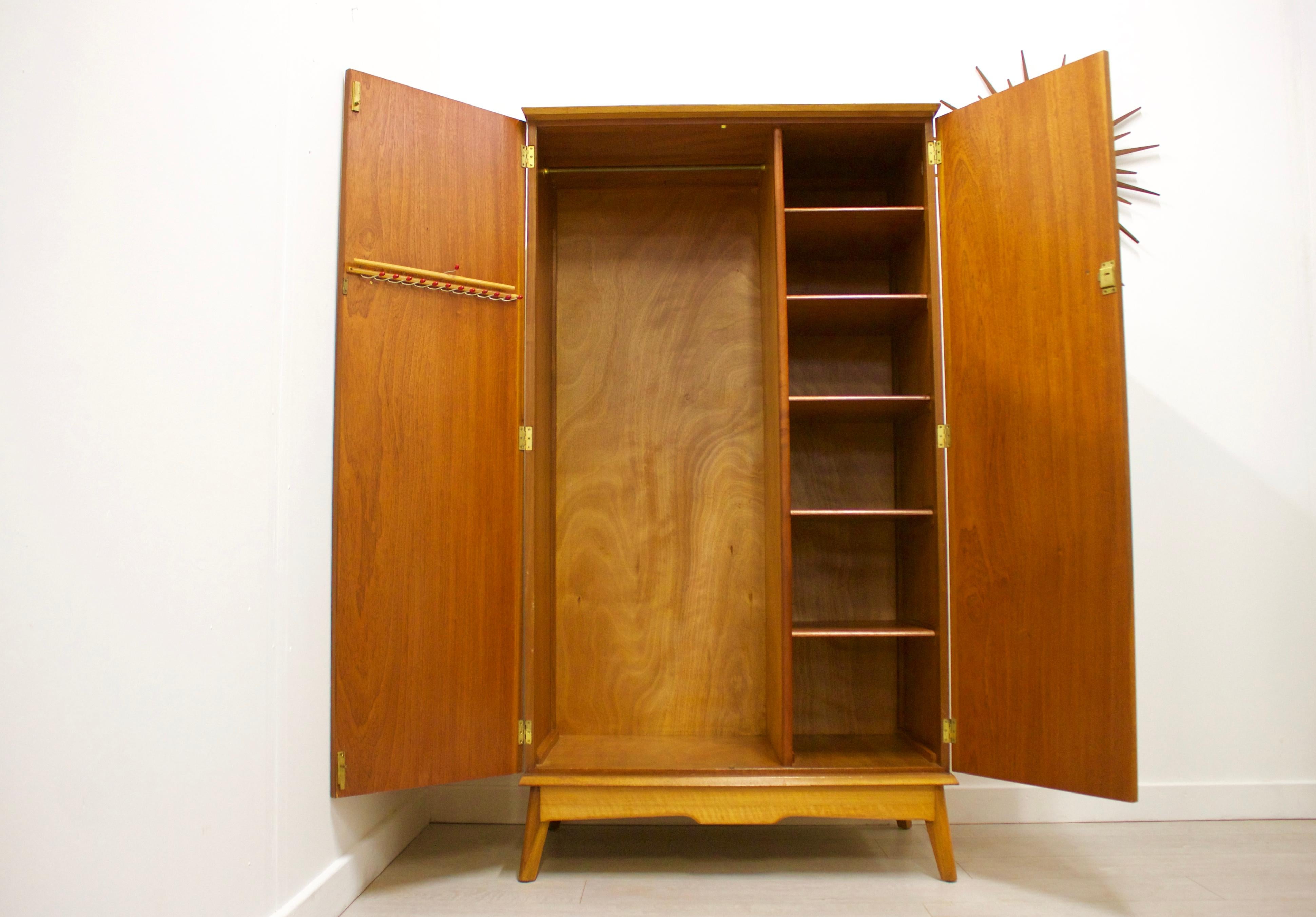 - Mid-Century Modern wardrobe
- Manufactured by Alfred Cox
- Made from walnut & walnut Veneer
- Featuring a hanging rail to the left, shelves to the right, and a tie rack on the left door.