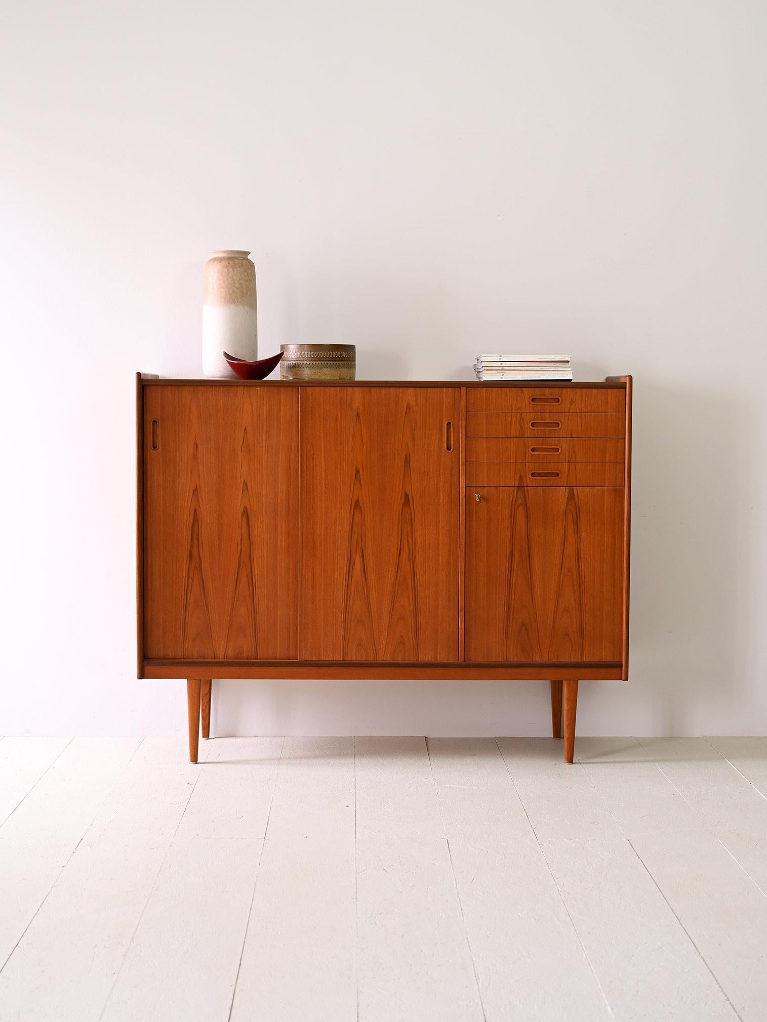 Simple, clean forms for this mid-century vintage Scandinavian teak wood sideboard/highboard.

Marked wood grain and classically Scandinavian shaped legs characterize this capacious sideboard.

Its strong point is its height of 120 cm and shallow