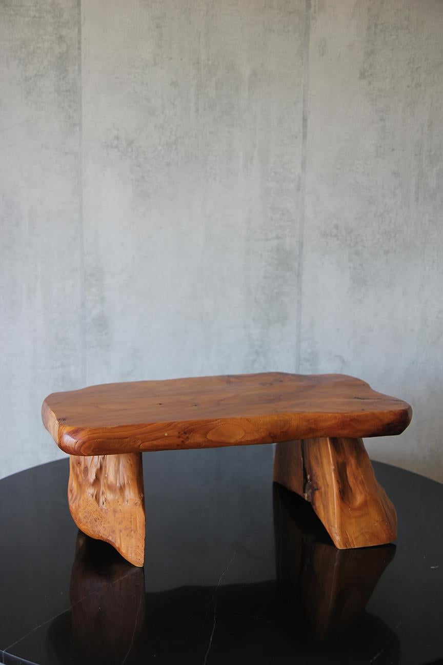 Dieser um 1960 in Frankreich gefertigte Holzhocker besticht durch sein minimalistisches Design mit einer Holzplatte, die anmutig auf vier Wurzelbeinen aus Teakholz ruht. Die Schlichtheit und Eleganz seiner Struktur verleihen jedem Wohnraum einen