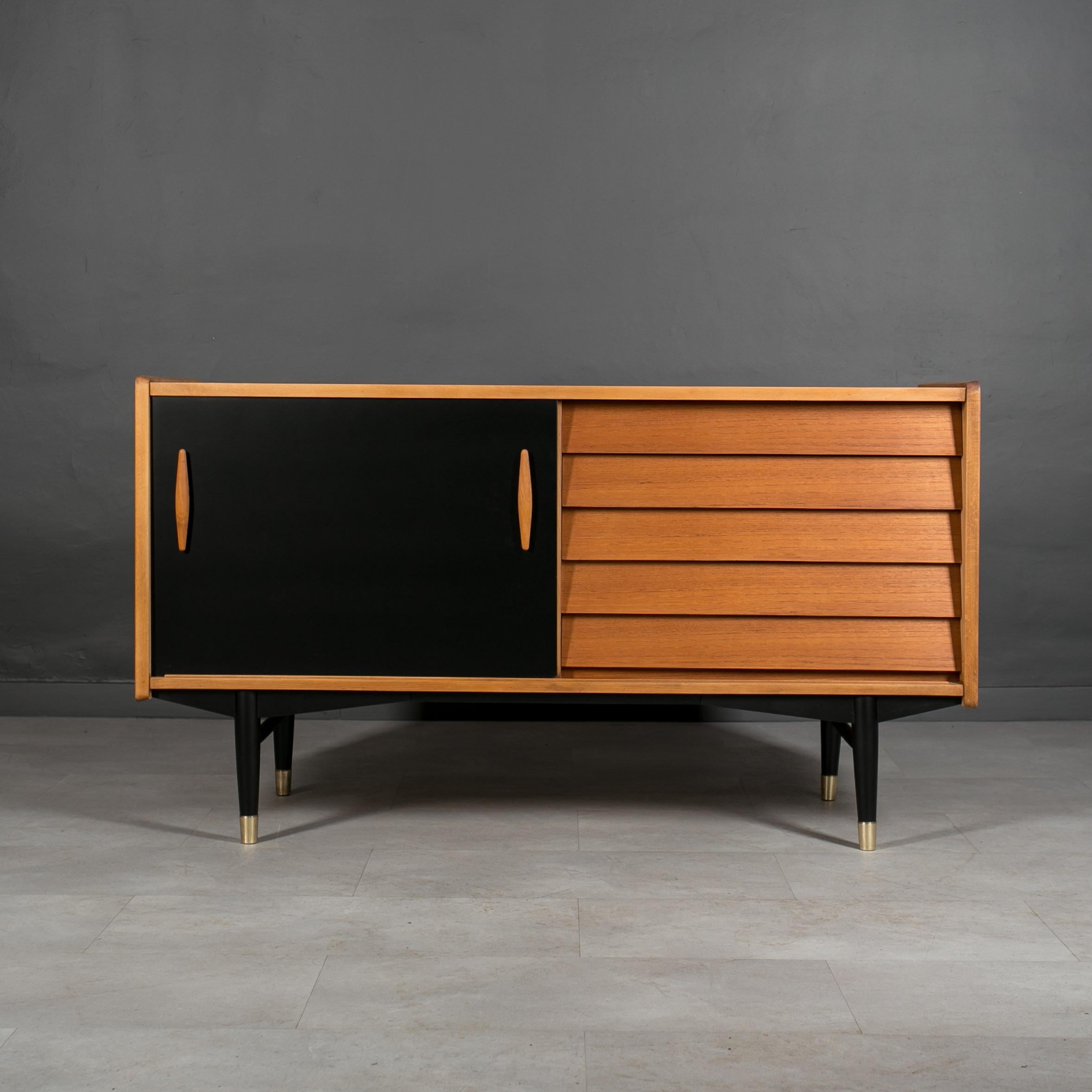 Discover the rare elegance of this distinctive teak wood sideboard, a unique design by Nils Jonsson exemplifying the timeless allure of Scandinavian Modern style. Crafted with precision and attention to detail, this remarkable piece features black
