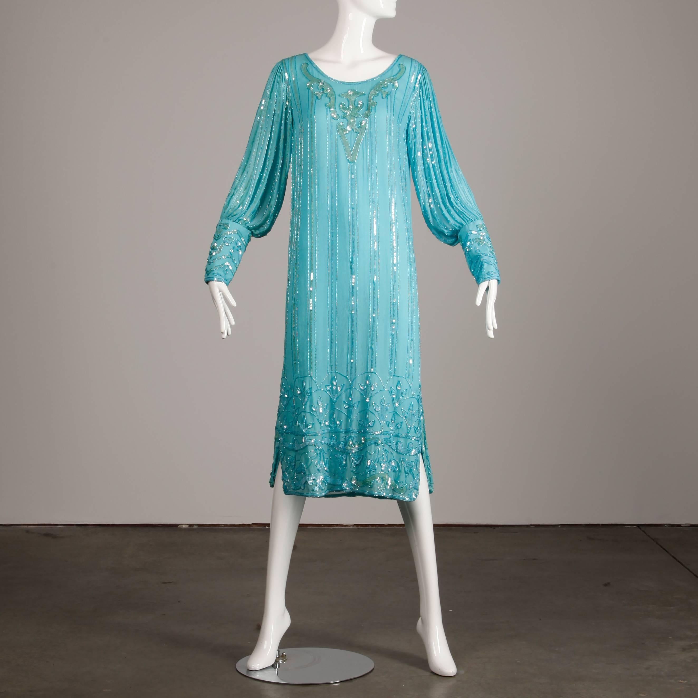 Vintage 1920s-inspired 1980s teal blue silk dress with hand done sequin and beadwork. Full blouson sleeves that zip at the cuff. Side slits. Fully lined in silk. The marked size is a medium, but the dress will also fit a modern size small. The bust